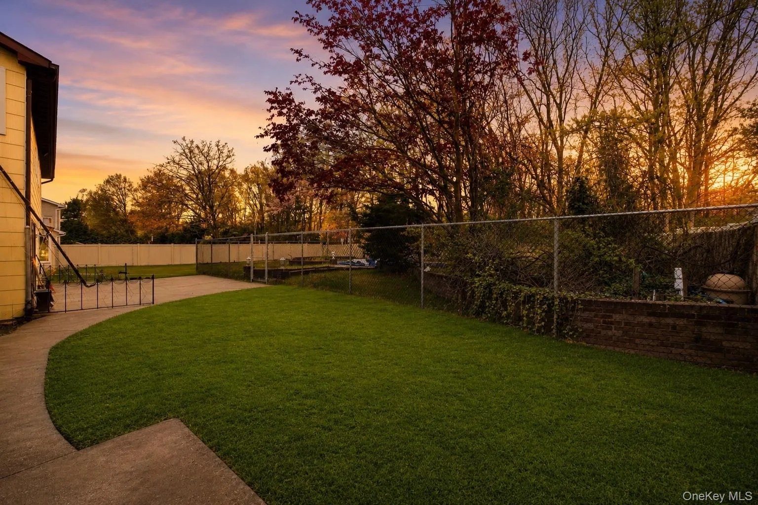 Expansive green lawn with a curved concrete pathway and a chain-link fence Expansive green lawn with a curved concrete pathway and a chain-link fence