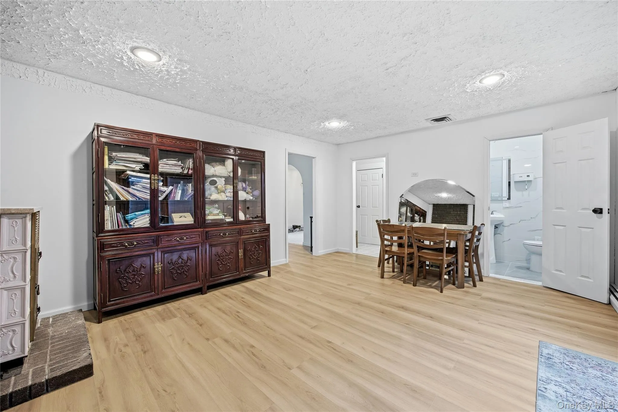 Open-concept living area featuring light wood-finish flooring, recessed lighting, and a white color palette Open-concept living area featuring light wood-finish flooring, recessed lighting, and a white color palette