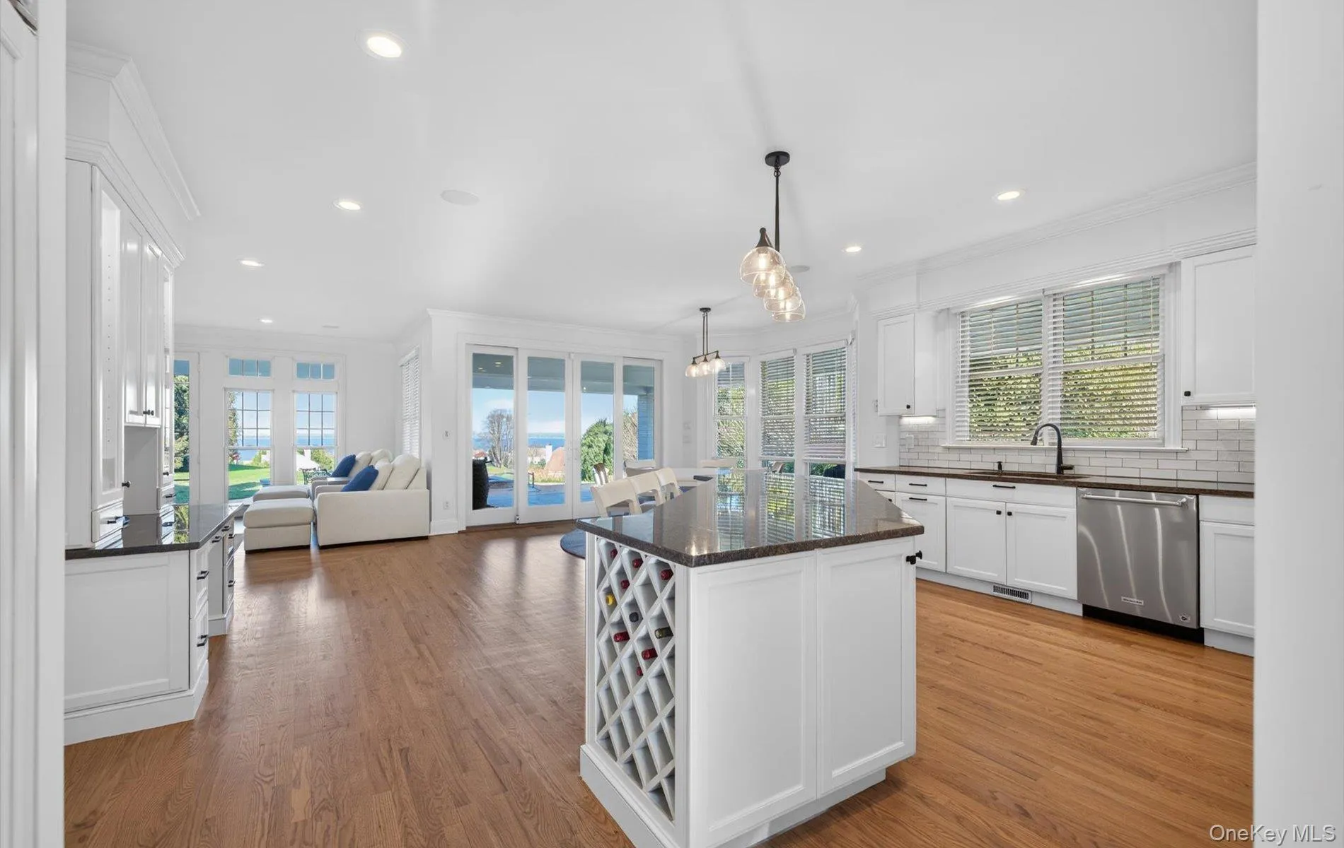 Open-concept kitchen and living area featuring wood-finish flooring, recessed lighting, and expansive glass doors Open-concept kitchen and living area featuring wood-finish flooring, recessed lighting, and expansive glass doors