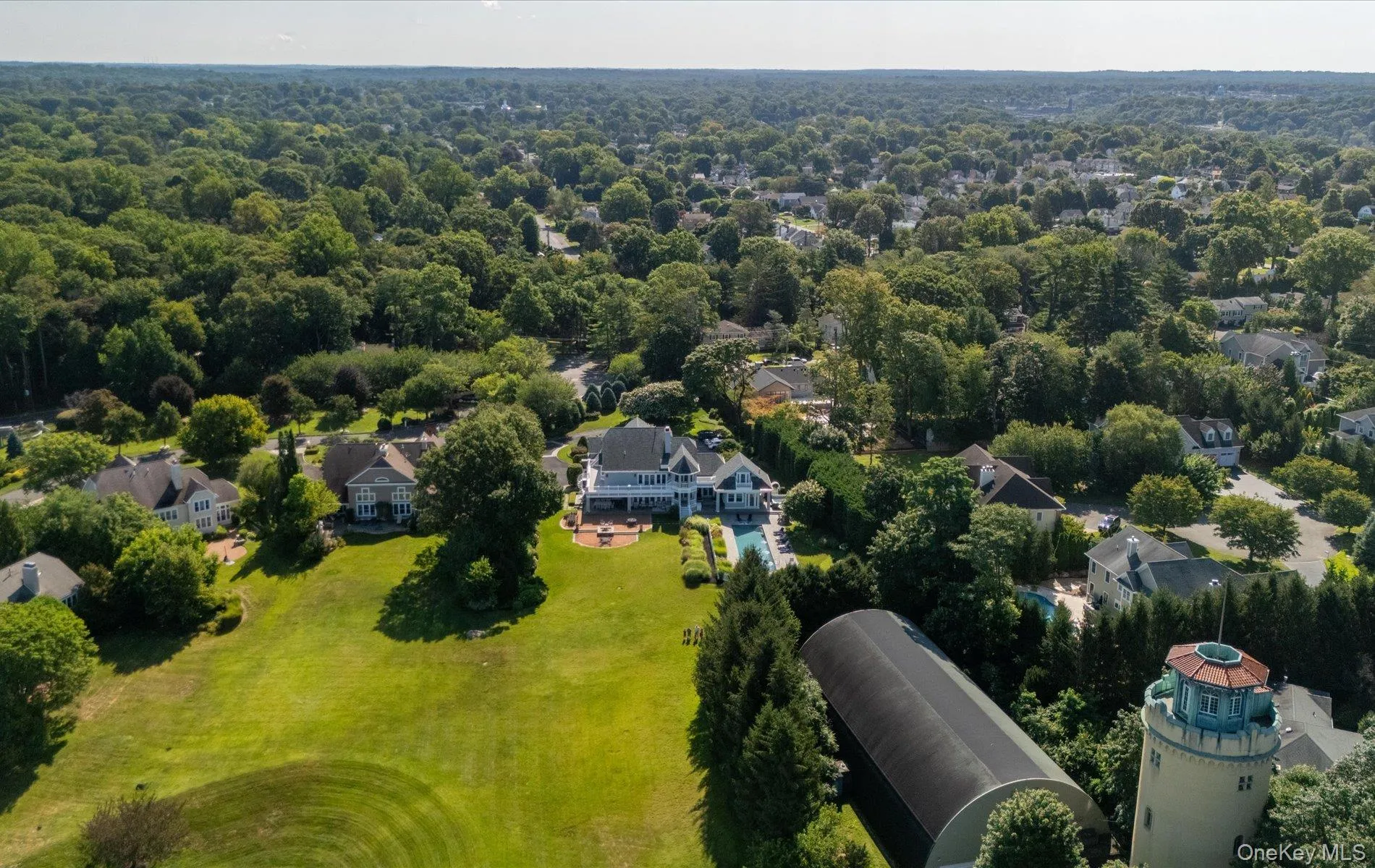 Expansive property featuring a meticulously manicured lawn, a large residential structure with a pool, and mature trees Expansive property featuring a meticulously manicured lawn, a large residential structure with a pool, and mature trees