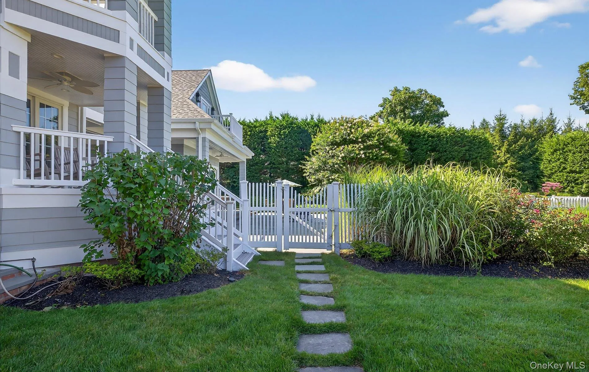 Manicured lawn with stepping stone pathway and white picket gate Manicured lawn with stepping stone pathway and white picket gate