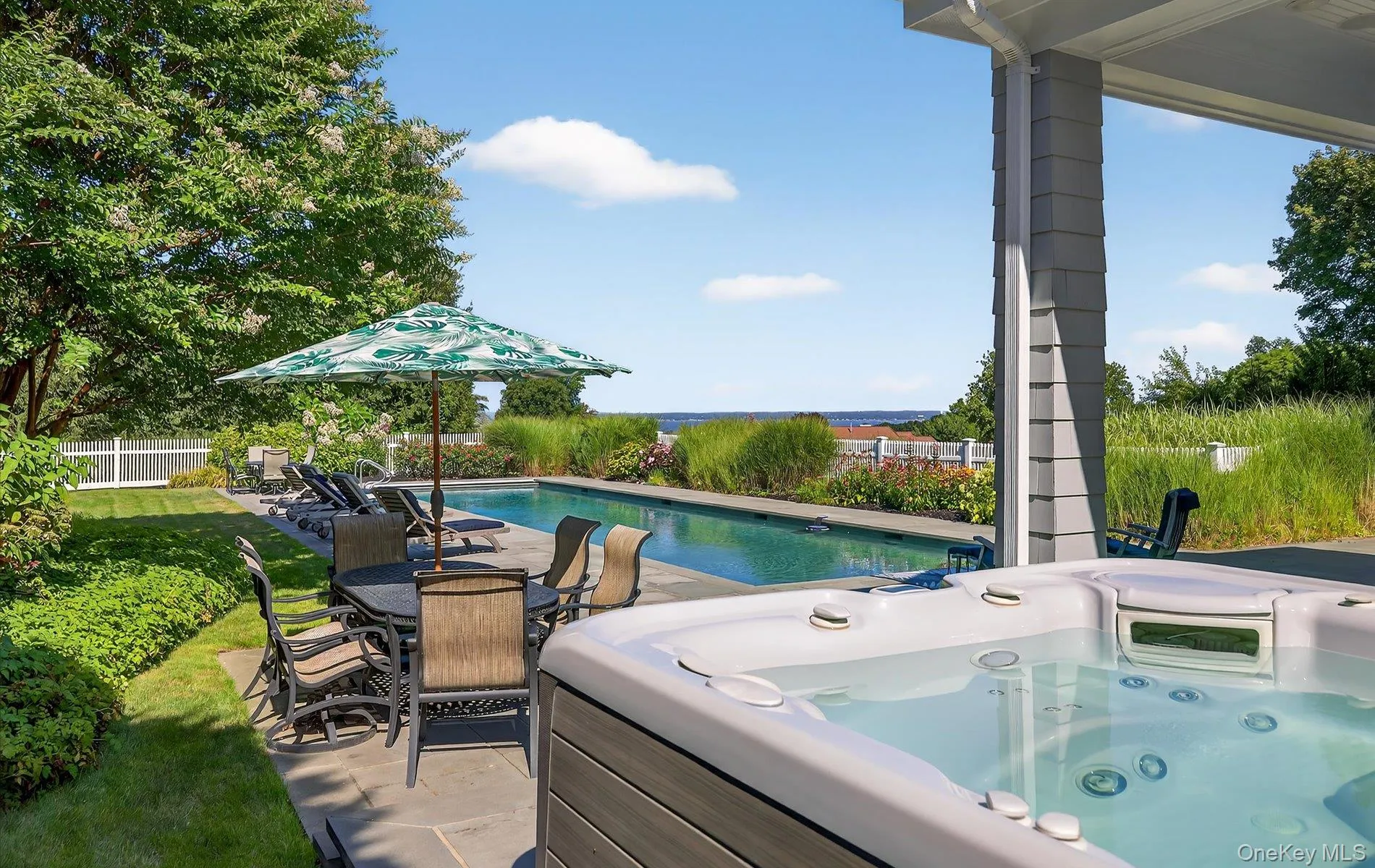 Outdoor entertaining space featuring a rectangular swimming pool, integrated hot tub, and stone patio Outdoor entertaining space featuring a rectangular swimming pool, integrated hot tub, and stone patio