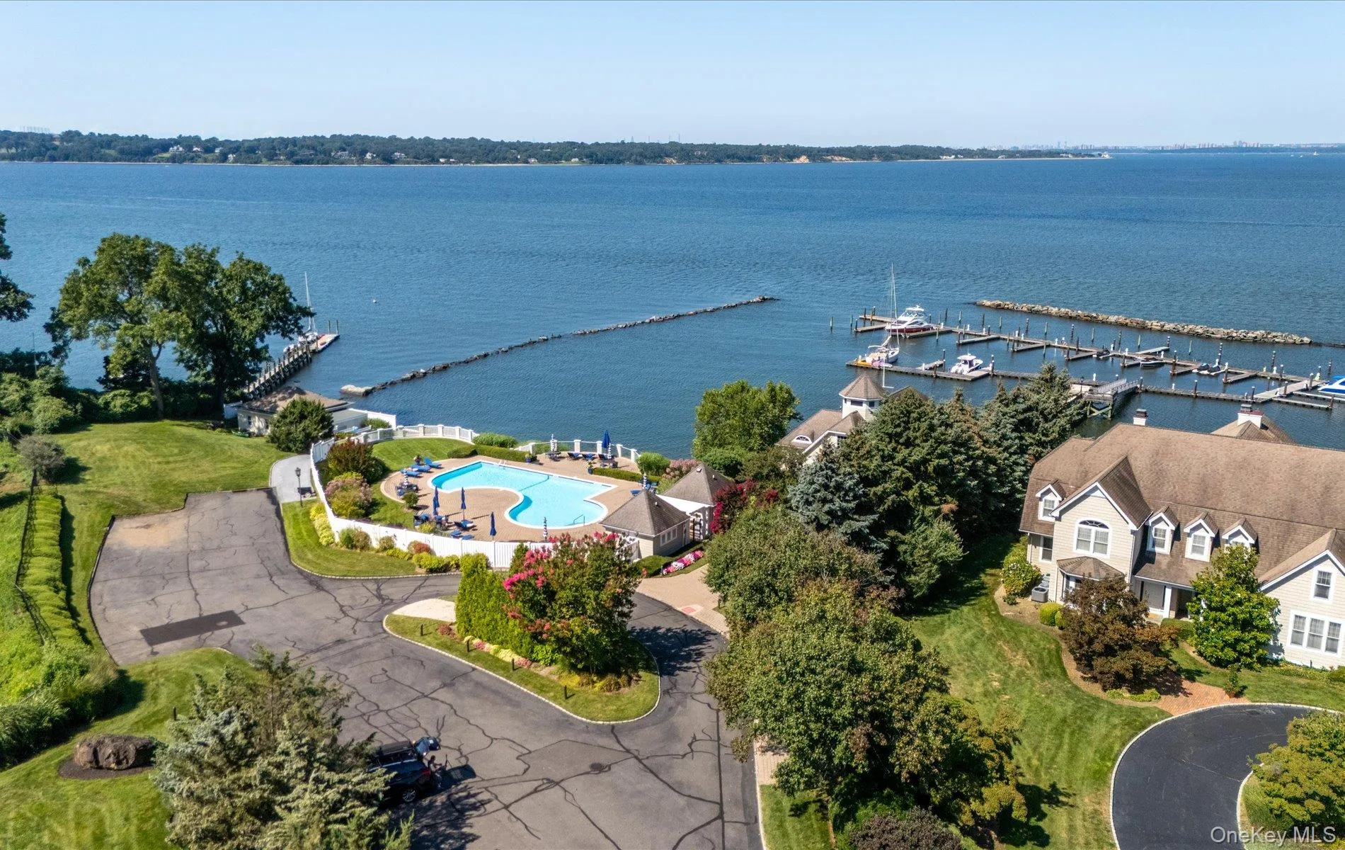 Waterfront property featuring a private marina, a freeform pool, and expansive green lawns Waterfront property featuring a private marina, a freeform pool, and expansive green lawns