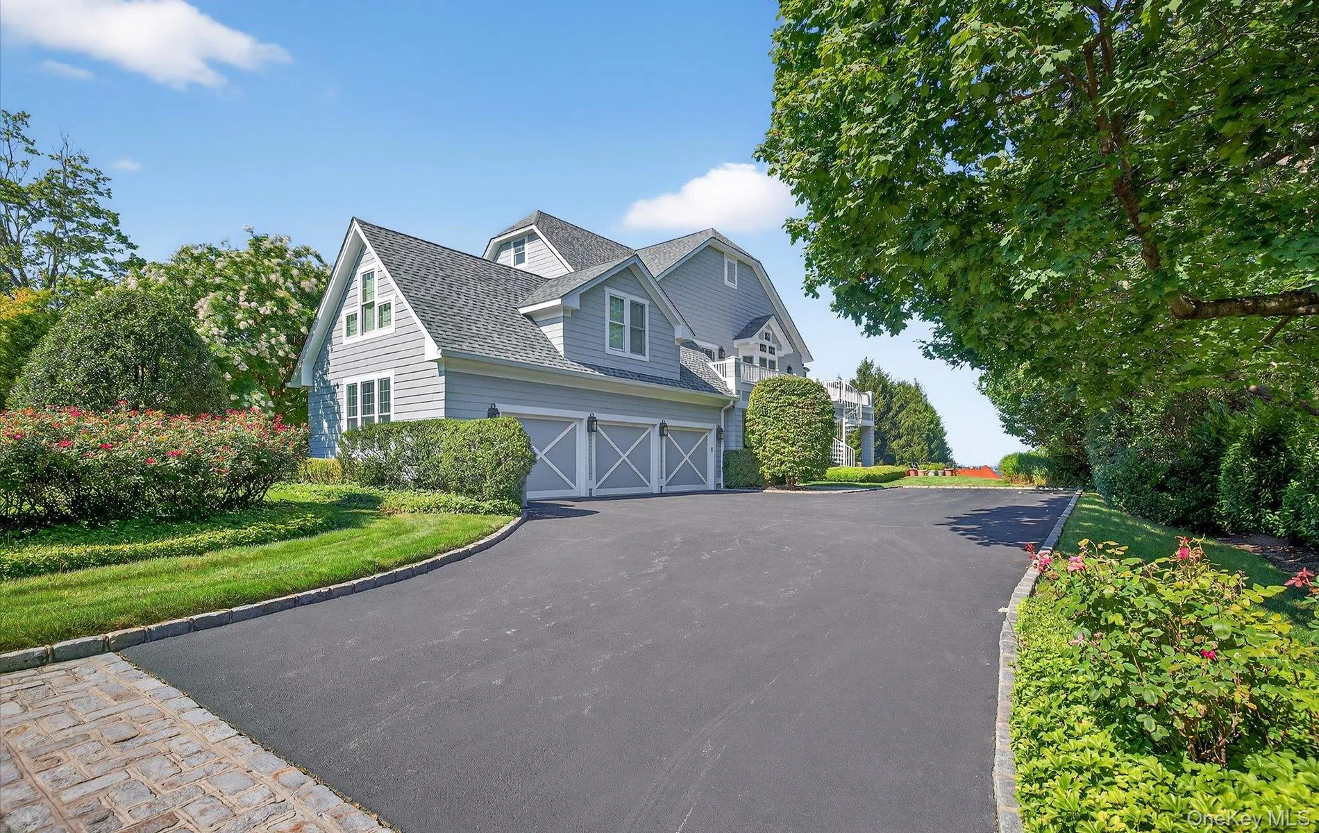 Shingle-style residence featuring light gray siding and a dark shingle roof Shingle-style residence featuring light gray siding and a dark shingle roof