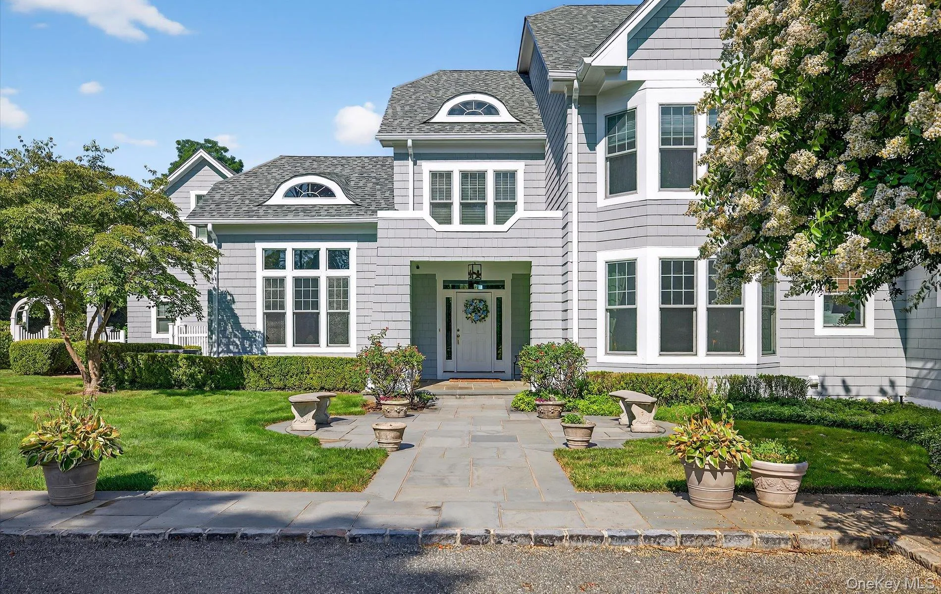 Traditional-style residence featuring light gray siding, white trim, and a prominent front entry with a transom window Traditional-style residence featuring light gray siding, white trim, and a prominent front entry with a transom window