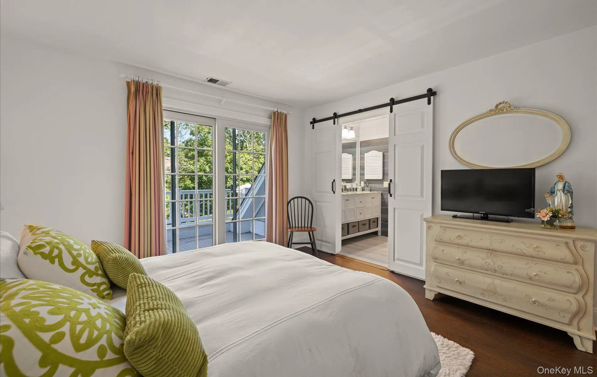 Bedroom featuring dark wood-finish flooring and direct access to a balcony through French doors Bedroom featuring dark wood-finish flooring and direct access to a balcony through French doors