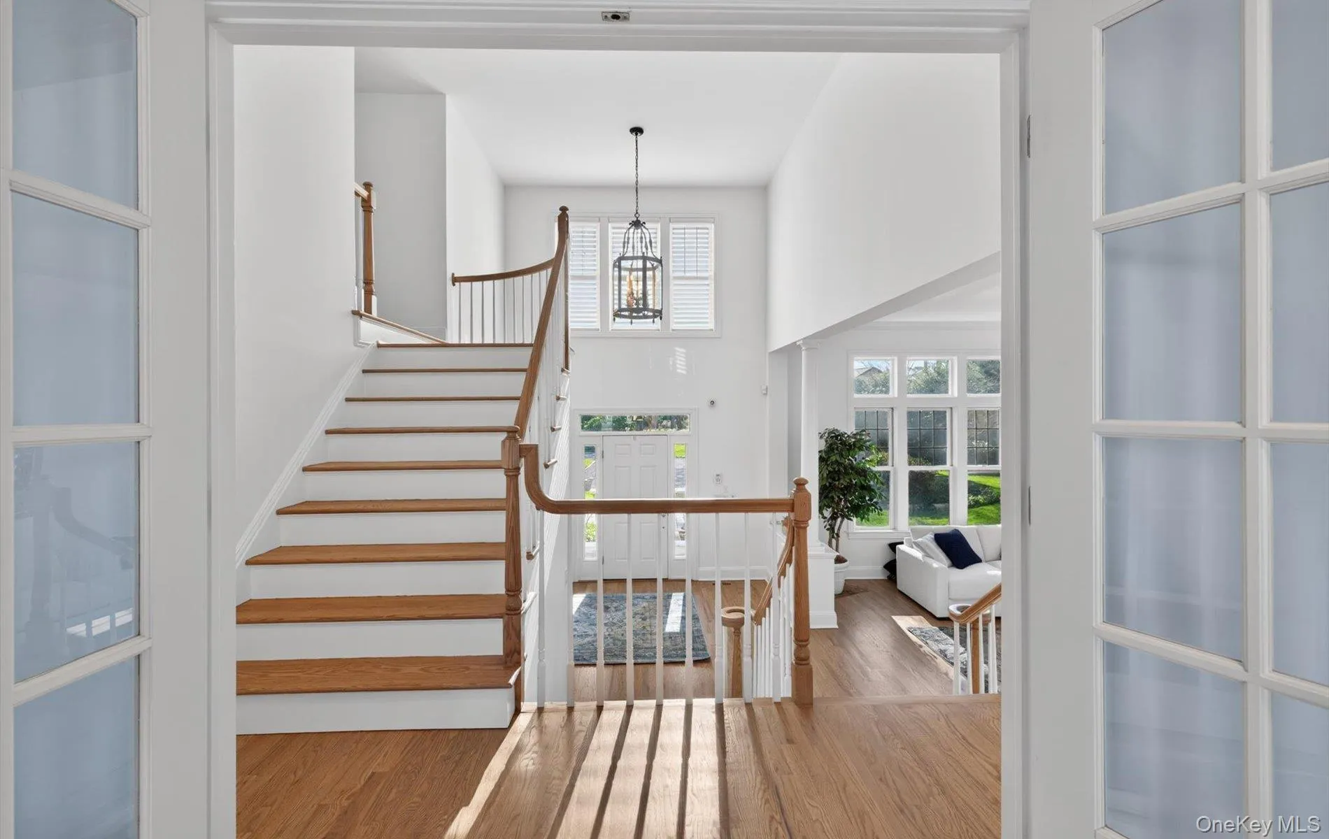 Grand entry foyer with a sweeping staircase featuring wood-finish treads and white risers Grand entry foyer with a sweeping staircase featuring wood-finish treads and white risers