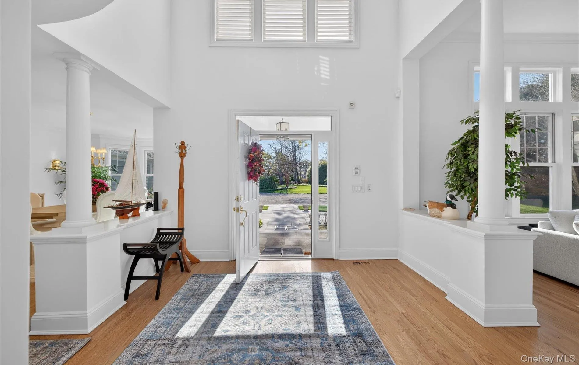 Grand entryway featuring a soaring ceiling, wood-finish flooring, and white interior columns Grand entryway featuring a soaring ceiling, wood-finish flooring, and white interior columns