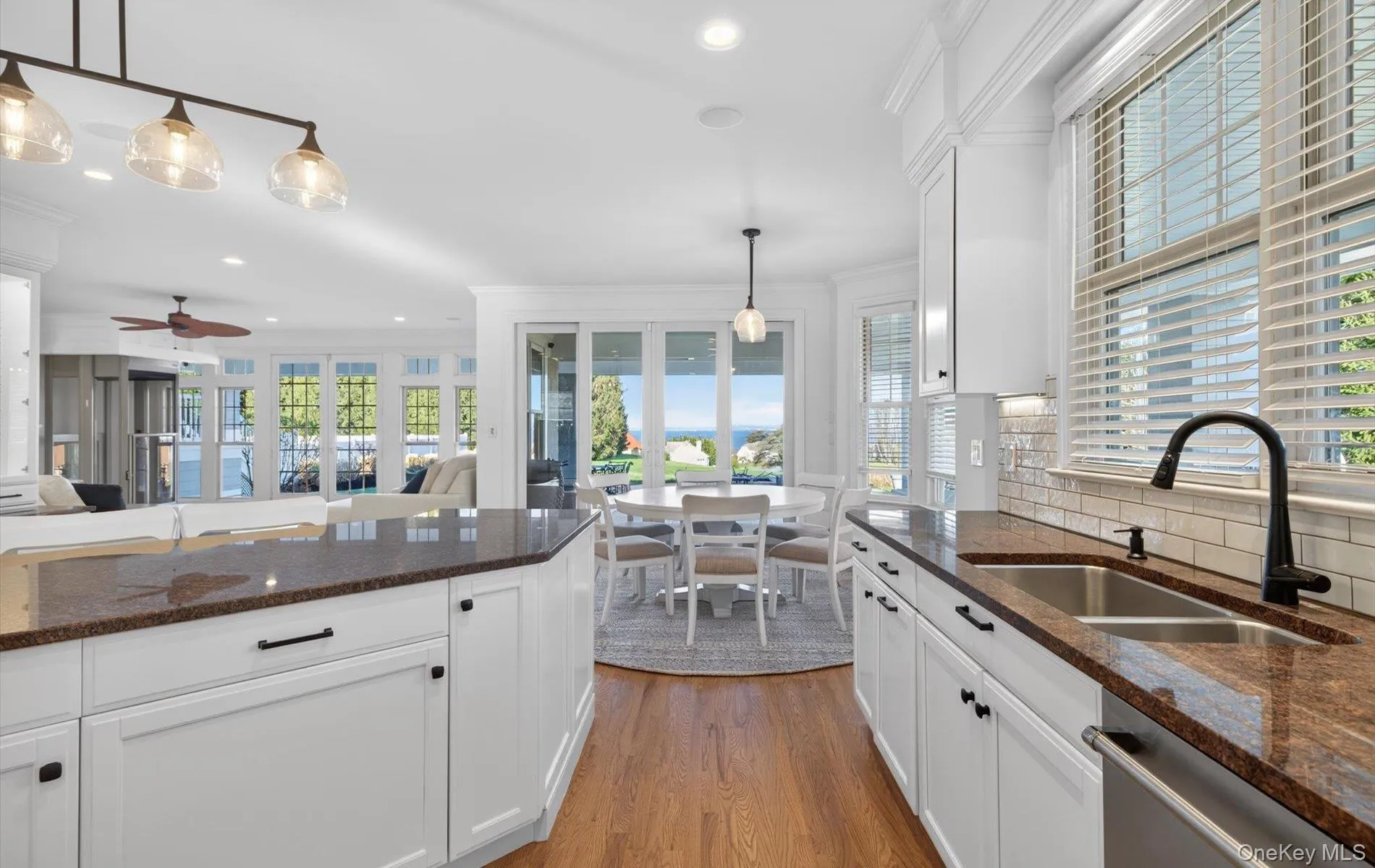 Kitchen featuring white cabinetry, dark stone countertops, a stainless steel sink with a matte black faucet, and subway tile backsplash Kitchen featuring white cabinetry, dark stone countertops, a stainless steel sink with a matte black faucet, and subway tile backsplash