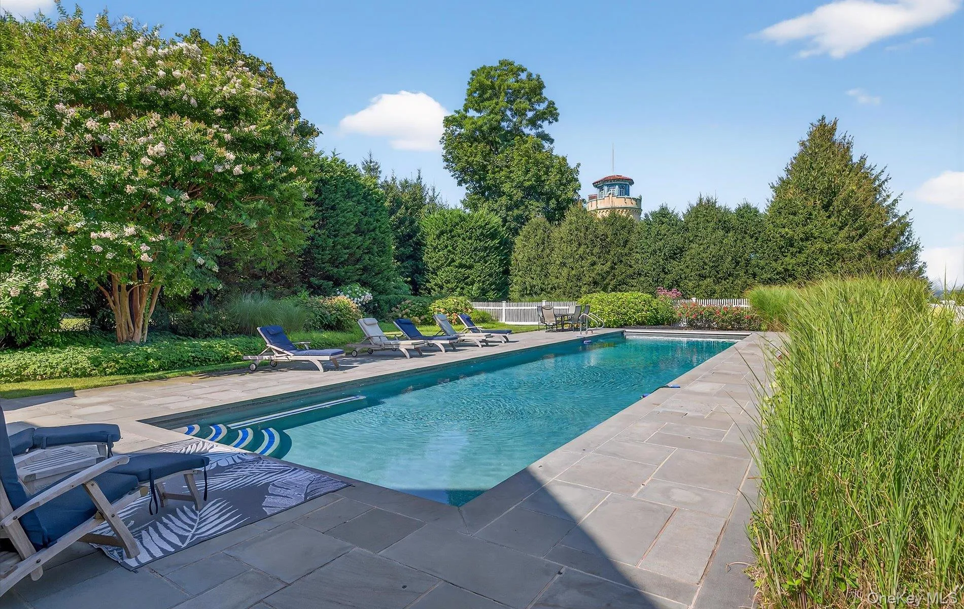 Elongated swimming pool with bluestone coping and surrounding patio Elongated swimming pool with bluestone coping and surrounding patio