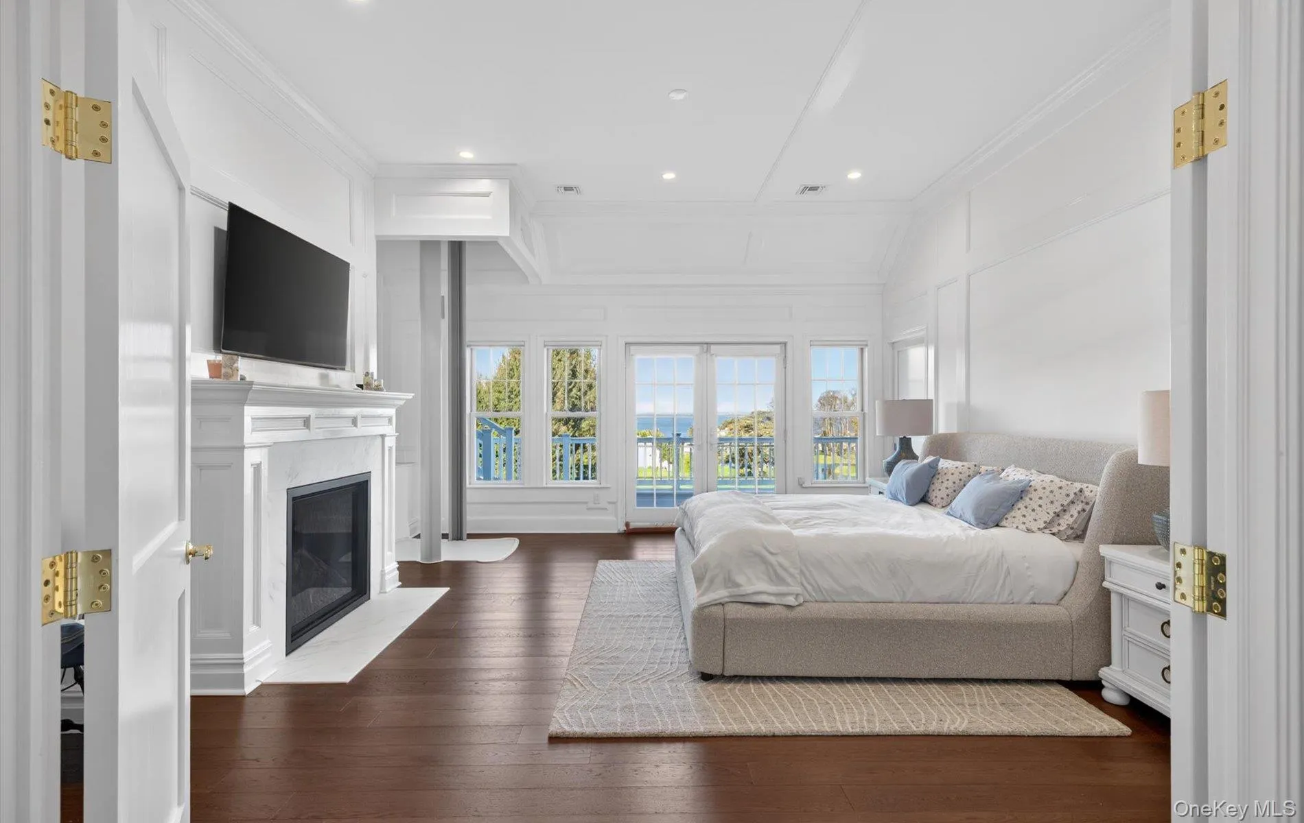 Spacious room featuring rich wood-finish flooring, a classic white mantel fireplace, and extensive white wainscoting Spacious room featuring rich wood-finish flooring, a classic white mantel fireplace, and extensive white wainscoting