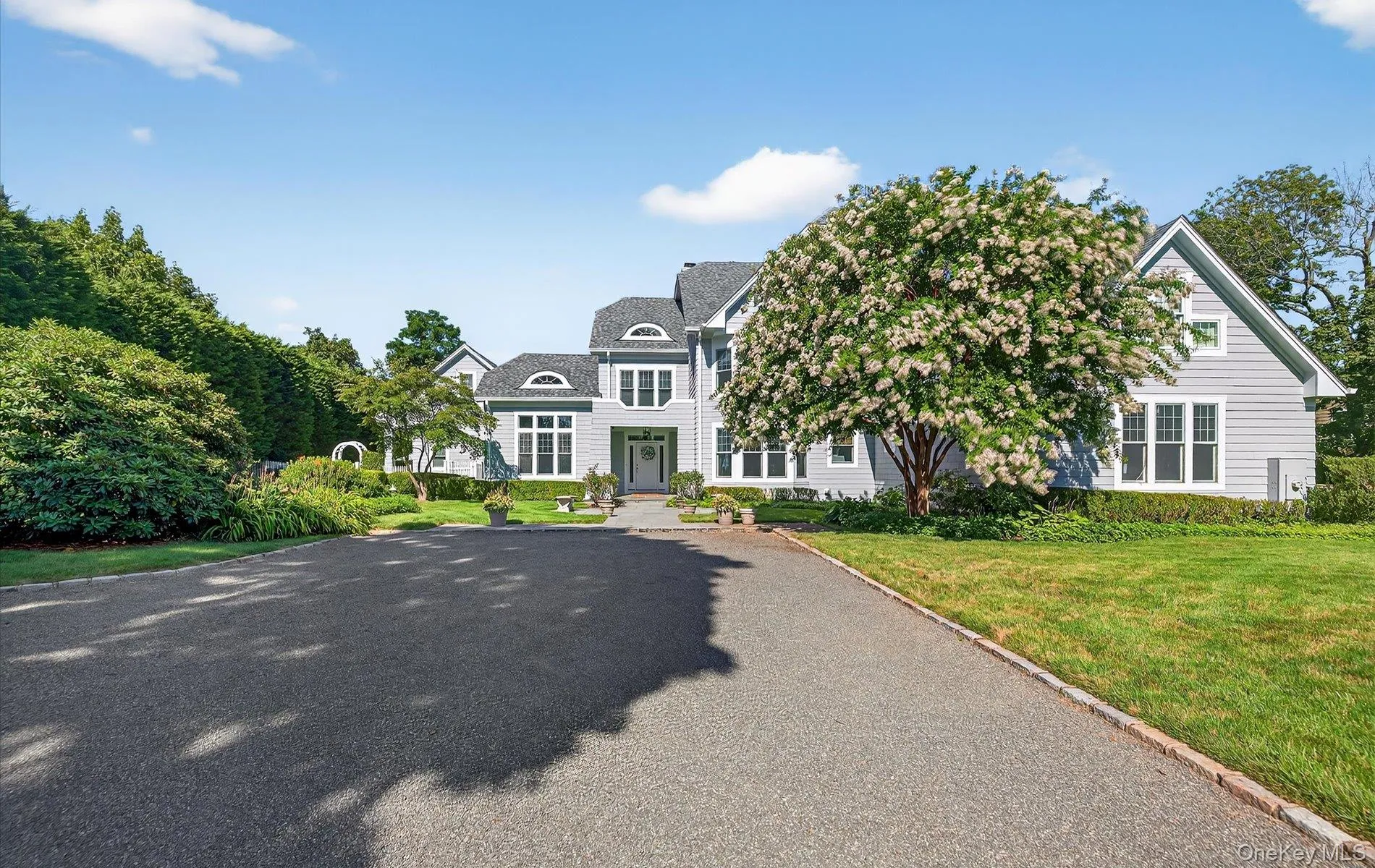 Expansive paved driveway leading to a multi-level residence with light grey siding Expansive paved driveway leading to a multi-level residence with light grey siding