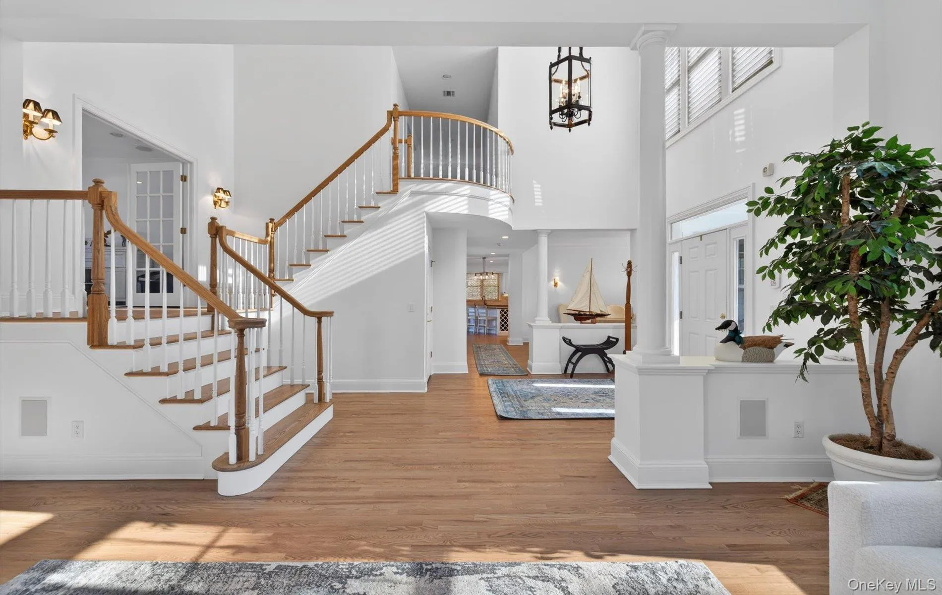 Grand foyer featuring a curved staircase with natural wood handrails and white balusters Grand foyer featuring a curved staircase with natural wood handrails and white balusters