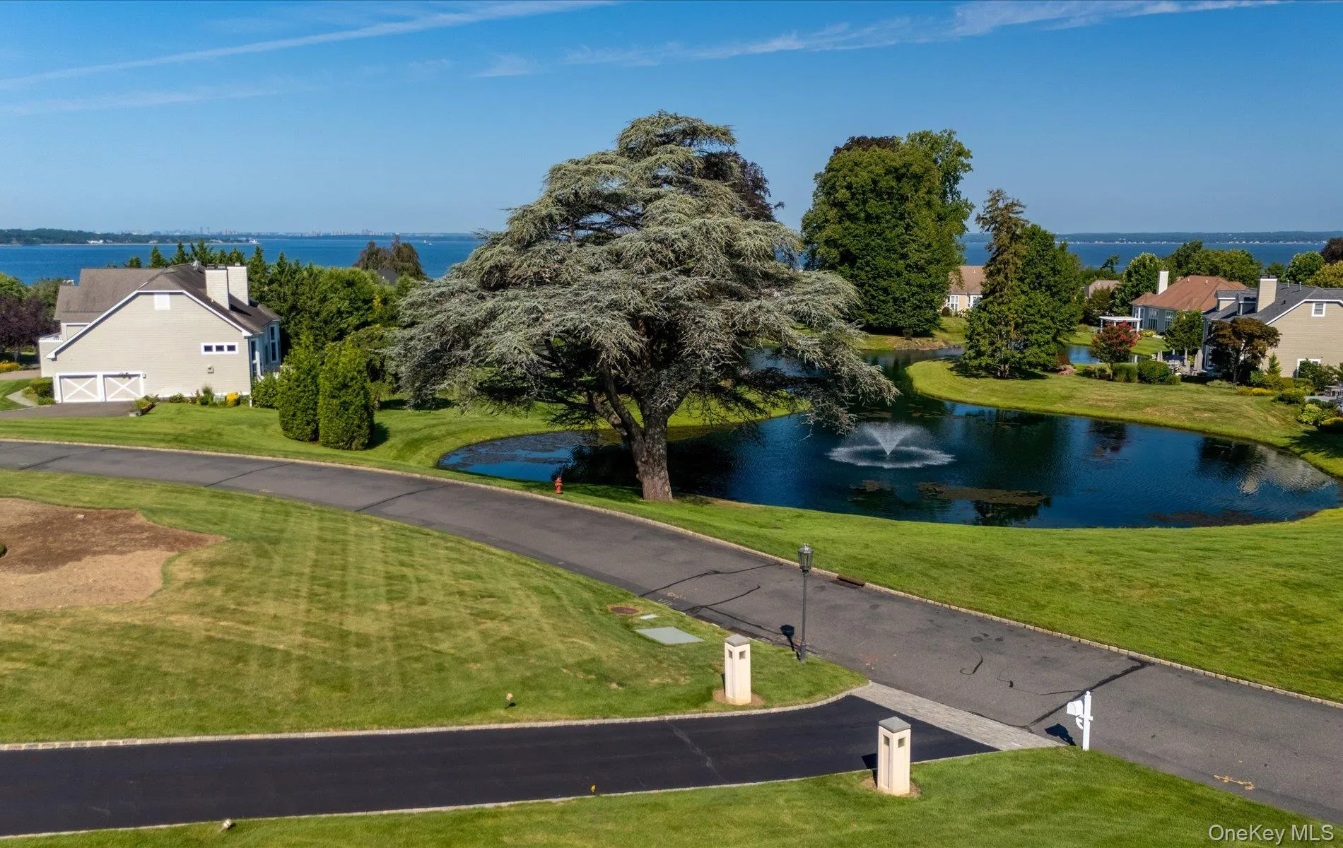 Expansive green lawn surrounds a serene pond with a central fountain feature Expansive green lawn surrounds a serene pond with a central fountain feature