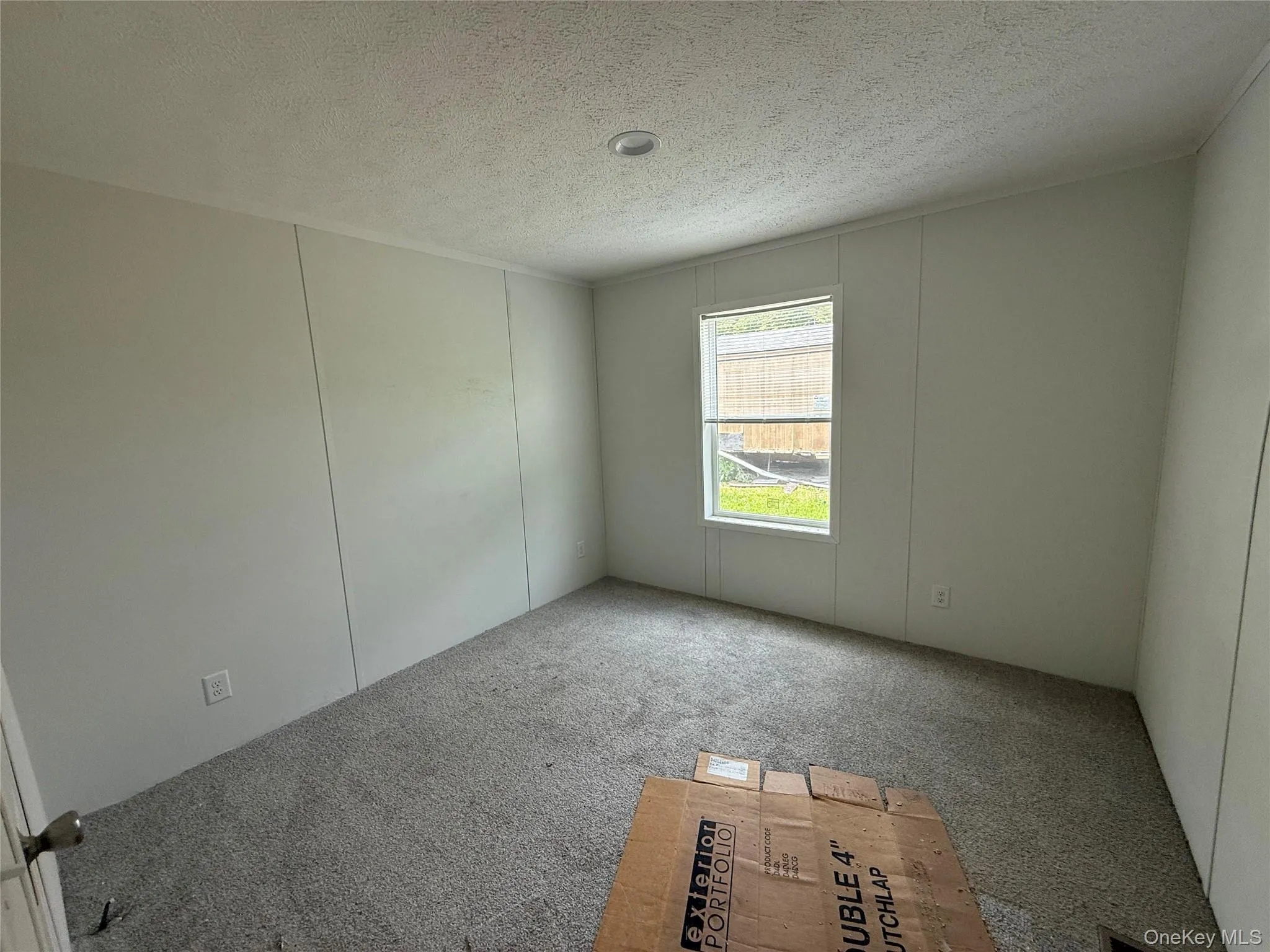 Carpeted empty room with a decorative wall and a textured ceiling Carpeted empty room with a decorative wall and a textured ceiling