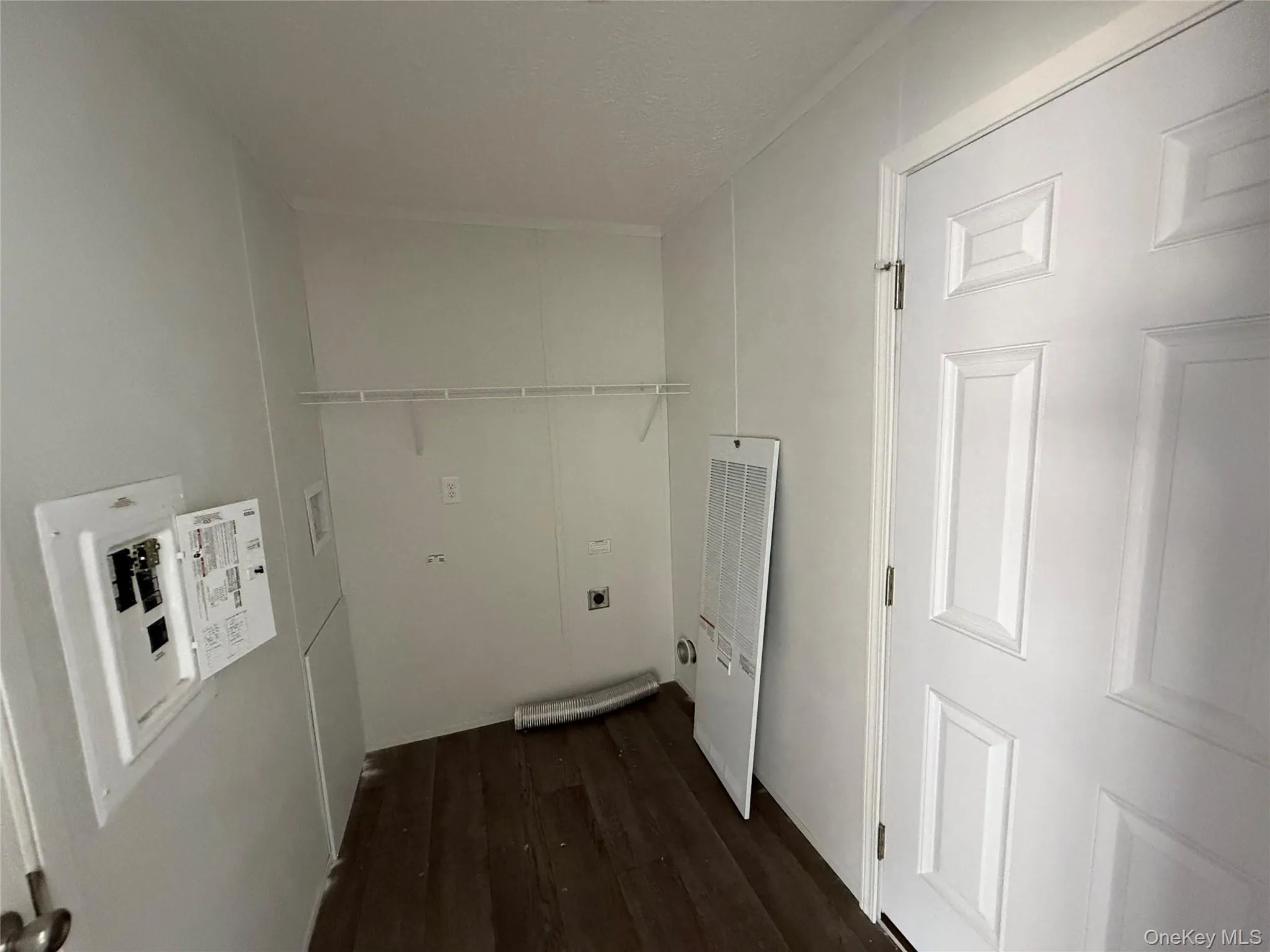 Laundry area featuring dark wood-style floors, a heating unit, a textured ceiling, and electric dryer hookup Laundry area featuring dark wood-style floors, a heating unit, a textured ceiling, and electric dryer hookup