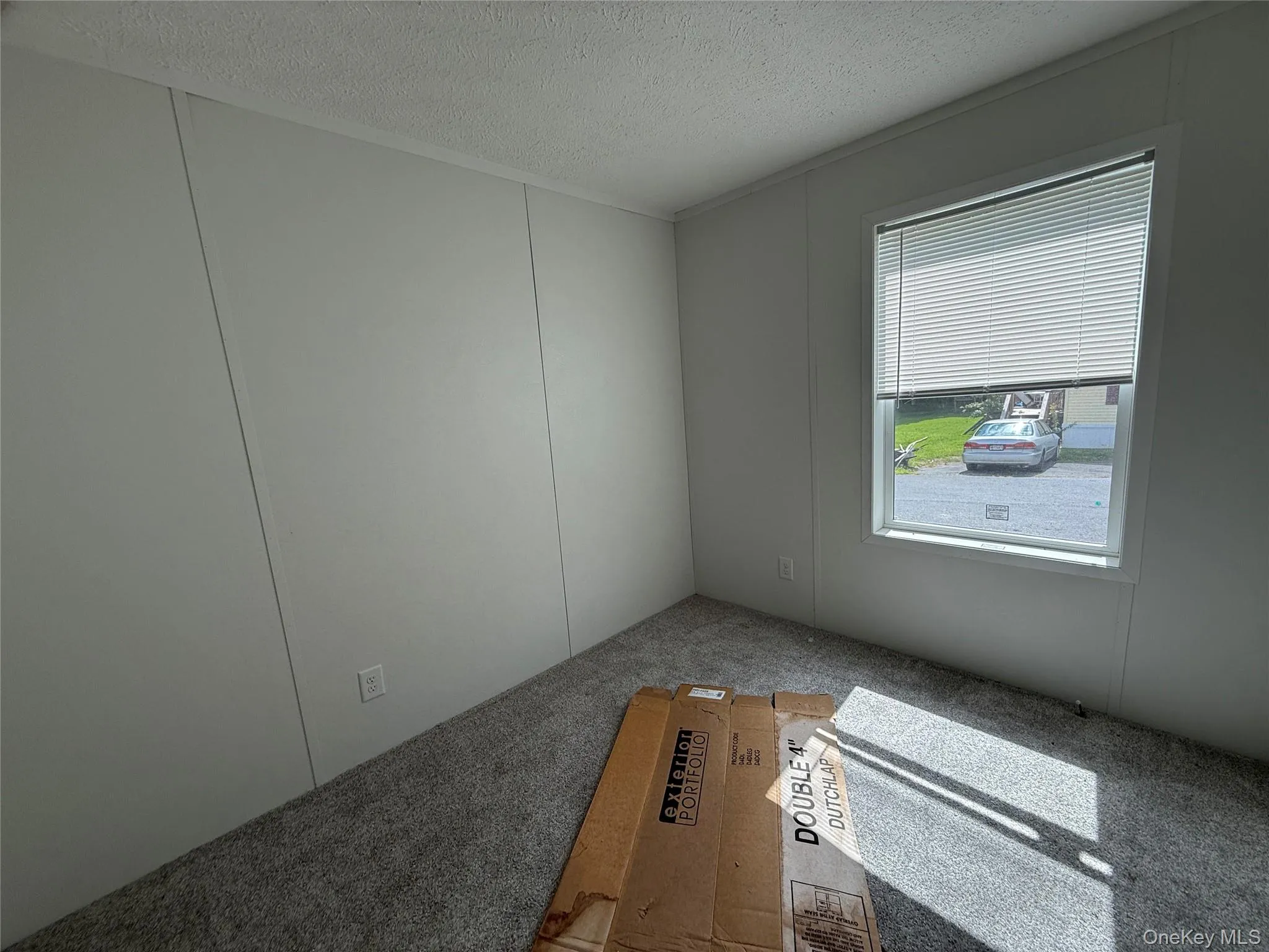 Spare room featuring a textured ceiling, a decorative wall, and carpet floors Spare room featuring a textured ceiling, a decorative wall, and carpet floors