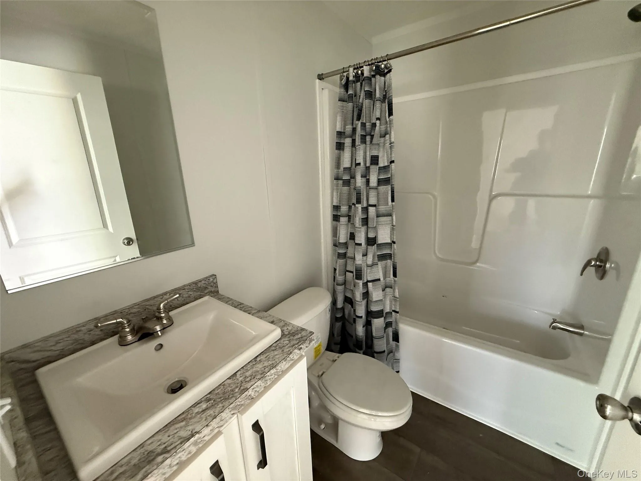 Bathroom featuring shower / bath combination with curtain, vanity, and dark wood-style floors Bathroom featuring shower / bath combination with curtain, vanity, and dark wood-style floors