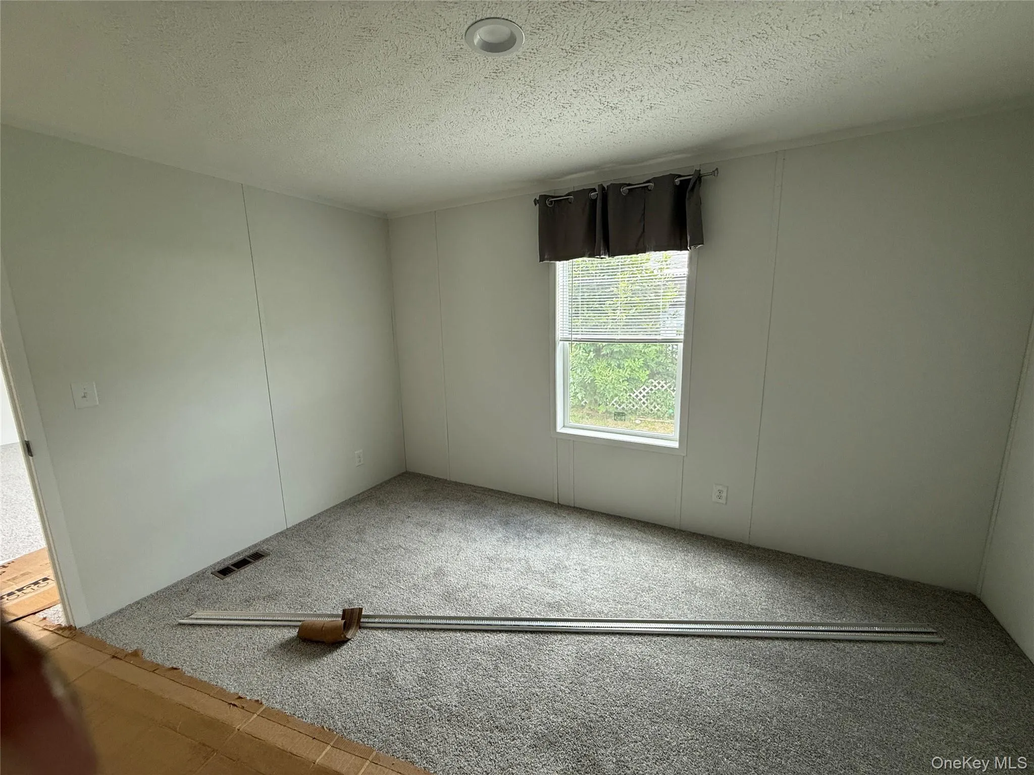 Spare room featuring carpet and a textured ceiling Spare room featuring carpet and a textured ceiling