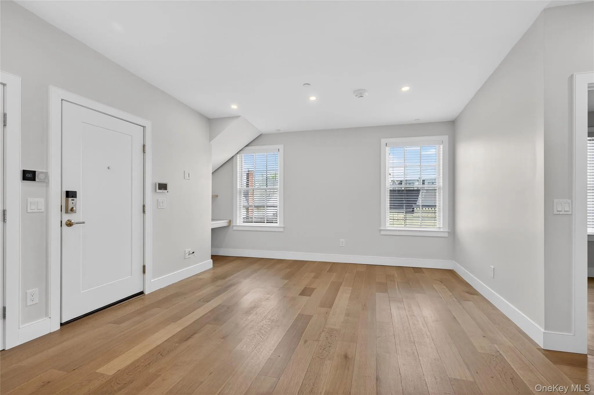 Spacious room featuring wide plank wood-finish flooring, recessed lighting, and bright windows with horizontal blinds Spacious room featuring wide plank wood-finish flooring, recessed lighting, and bright windows with horizontal blinds