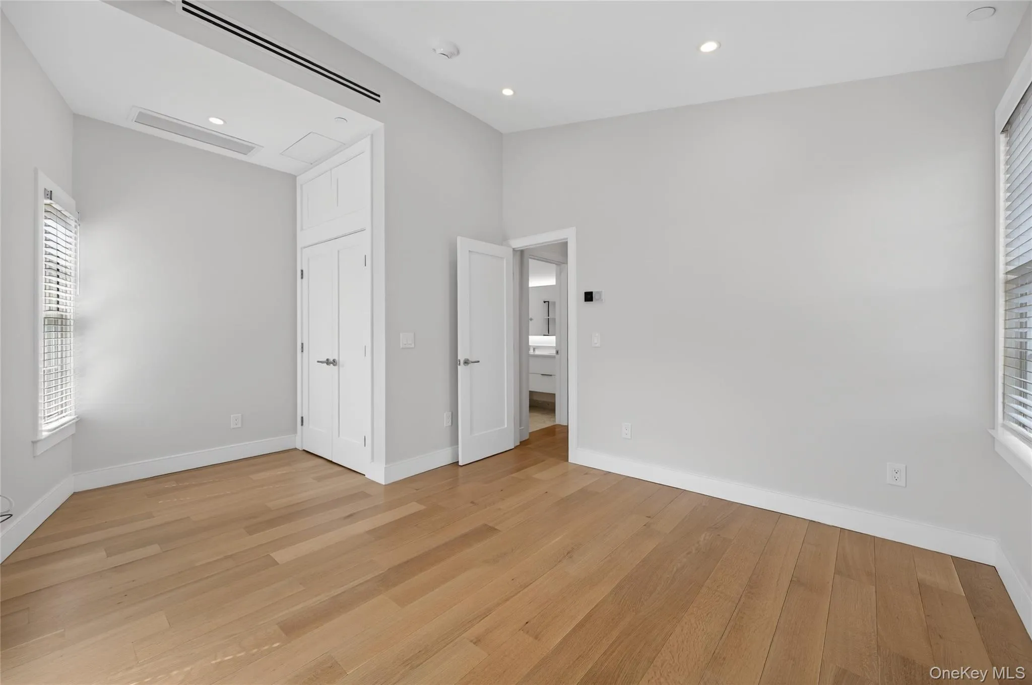 Spacious interior with light wood-finish flooring, recessed lighting, and a built-in closet with double doors Spacious interior with light wood-finish flooring, recessed lighting, and a built-in closet with double doors