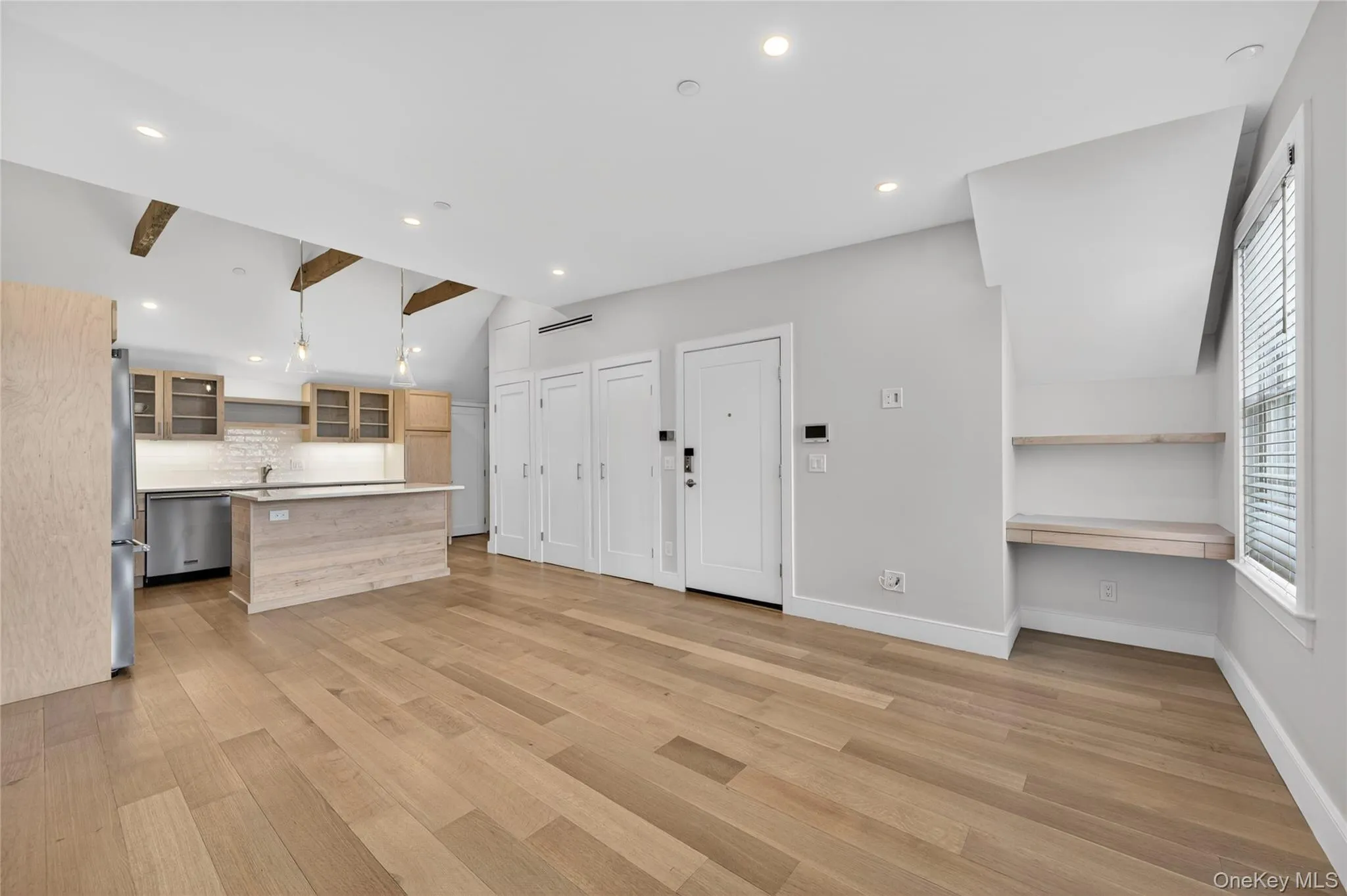 Open-concept living area featuring wide-plank wood-finish flooring, recessed lighting, and exposed ceiling beams Open-concept living area featuring wide-plank wood-finish flooring, recessed lighting, and exposed ceiling beams