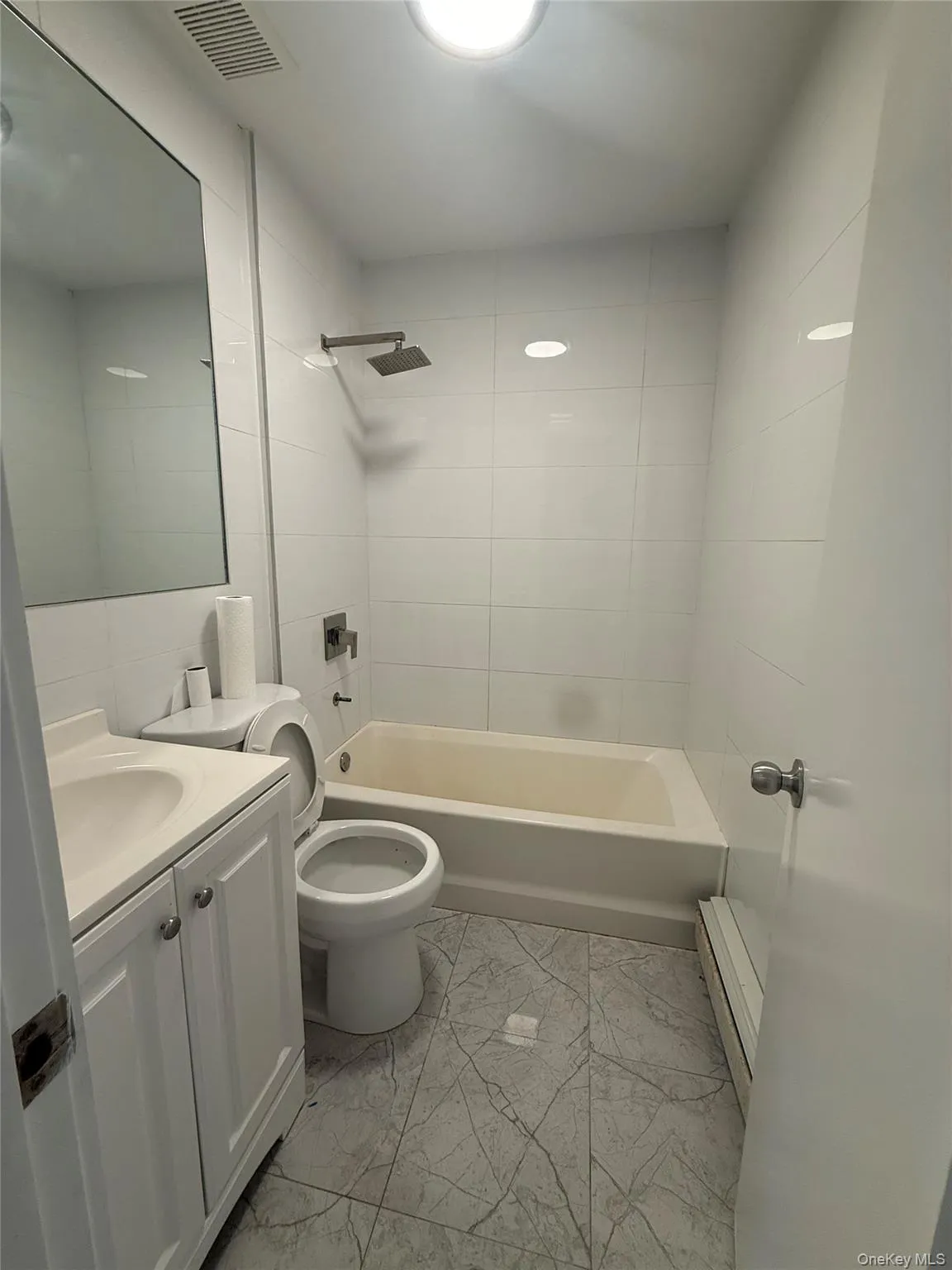 Bathroom with white tile walls and a light-colored bathtub Bathroom with white tile walls and a light-colored bathtub