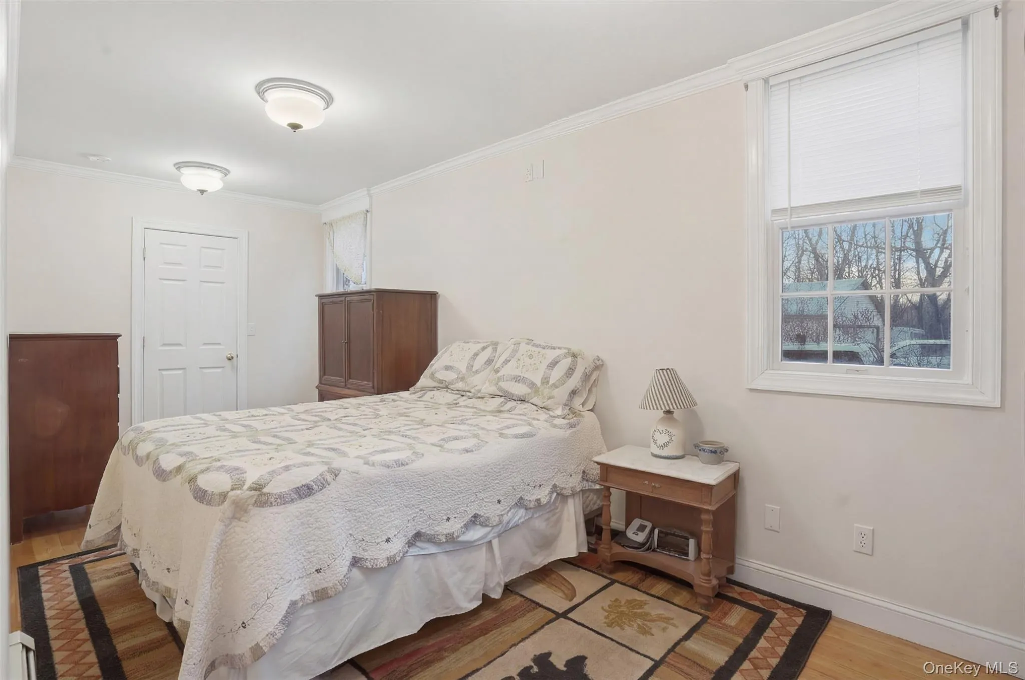 Bright room featuring light-toned walls, wood-finish flooring, white trim, and a white paneled door Bright room featuring light-toned walls, wood-finish flooring, white trim, and a white paneled door