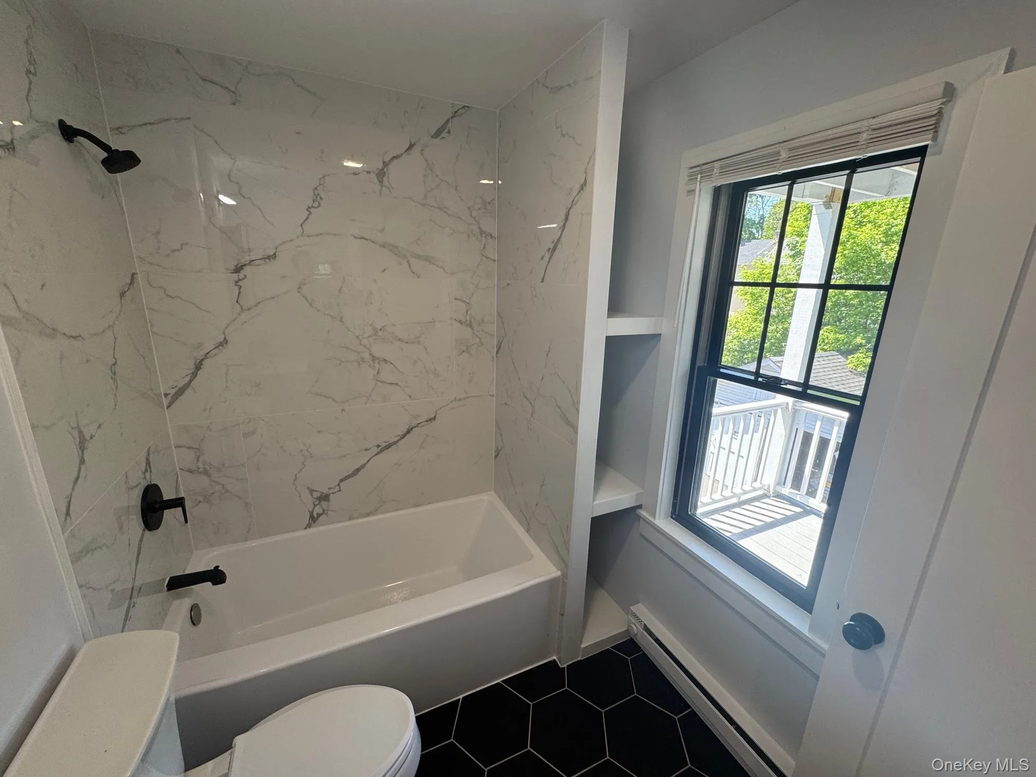 Bathroom with toilet, healthy amount of natural light, baseboard heating, and washtub / shower combination Bathroom with toilet, healthy amount of natural light, baseboard heating, and washtub / shower combination