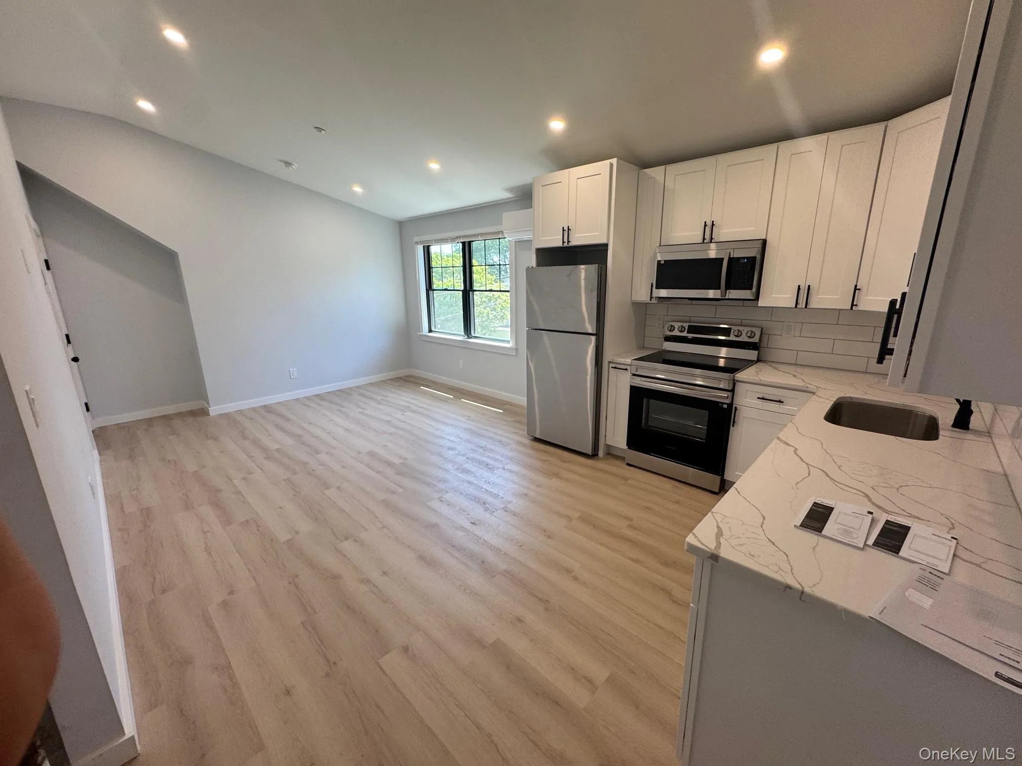 Kitchen with stainless steel appliances, light stone counters, recessed lighting, decorative backsplash, and a sink Kitchen with stainless steel appliances, light stone counters, recessed lighting, decorative backsplash, and a sink
