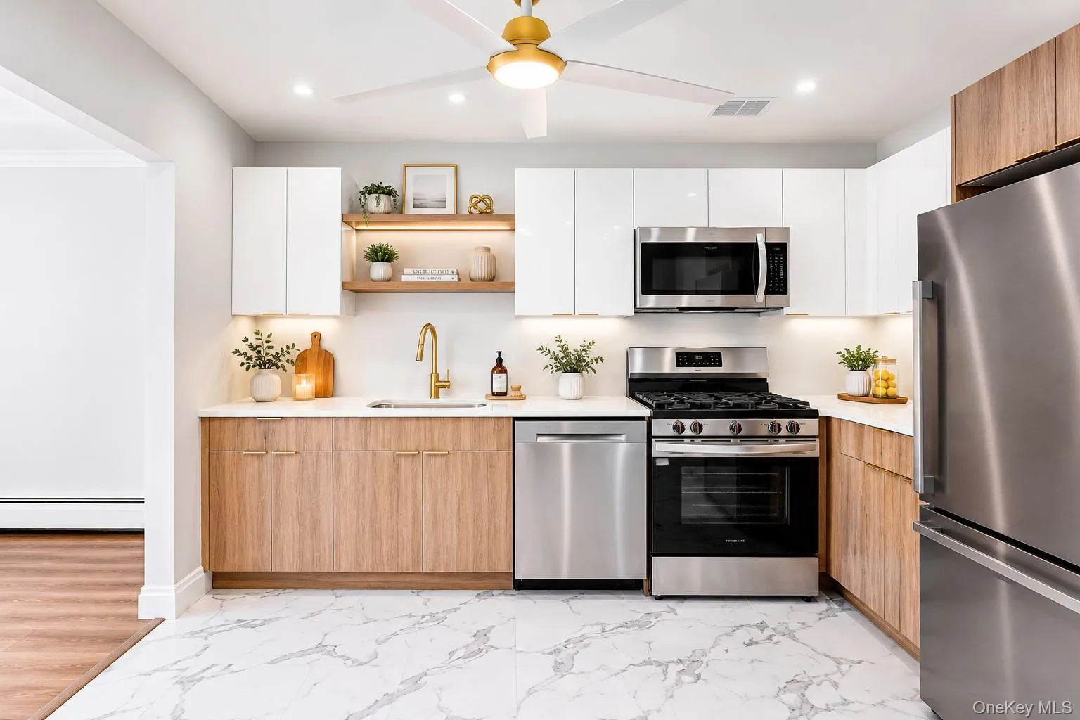 Modern kitchen featuring two-tone cabinetry, stainless steel appliances, a brass faucet, and marble-look flooring (PROPS ON COUNTER VIRTUALLY ADDED) Modern kitchen featuring two-tone cabinetry, stainless steel appliances, a brass faucet, and marble-look flooring (PROPS ON COUNTER VIRTUALLY ADDED)