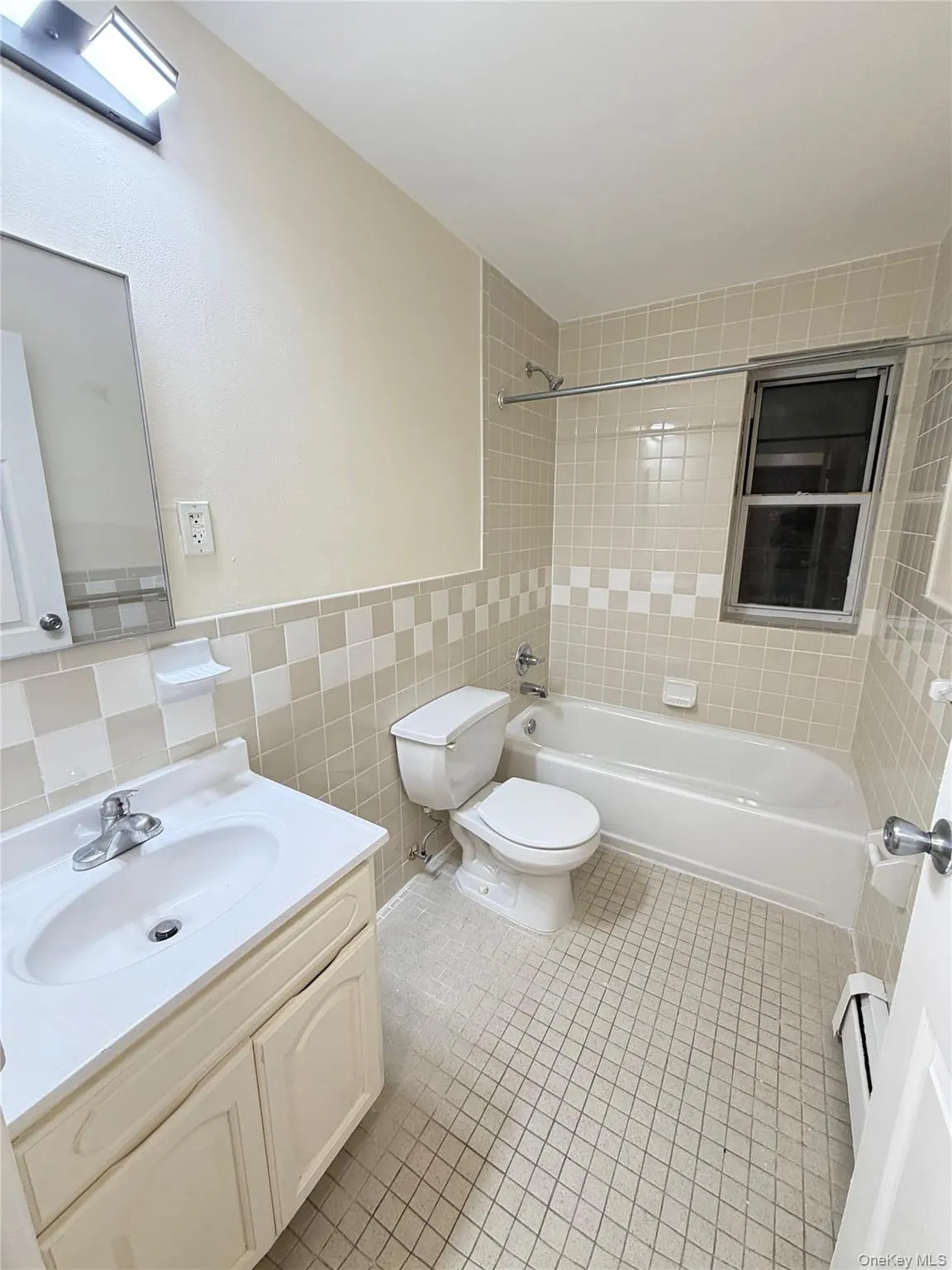 Bathroom featuring a built-in bathtub with shower, tiled walls, and a window Bathroom featuring a built-in bathtub with shower, tiled walls, and a window