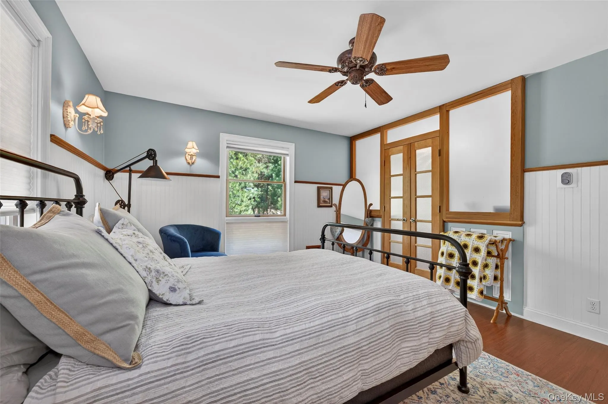 Interior space featuring wood-finish flooring, wainscoting, and a ceiling fan Interior space featuring wood-finish flooring, wainscoting, and a ceiling fan