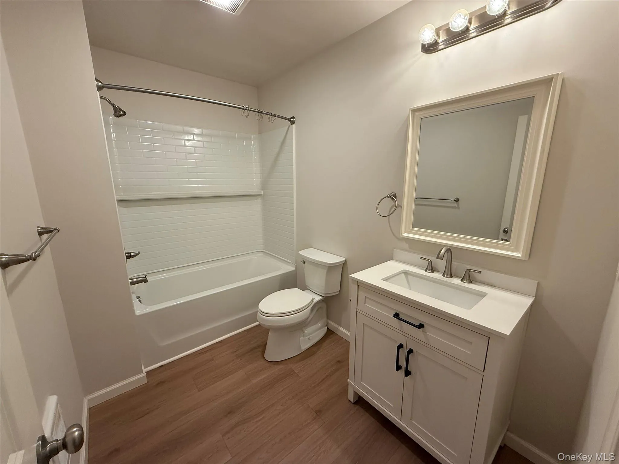 Full bath with shower / bath combination, vanity, and dark wood-type flooring Full bath with shower / bath combination, vanity, and dark wood-type flooring