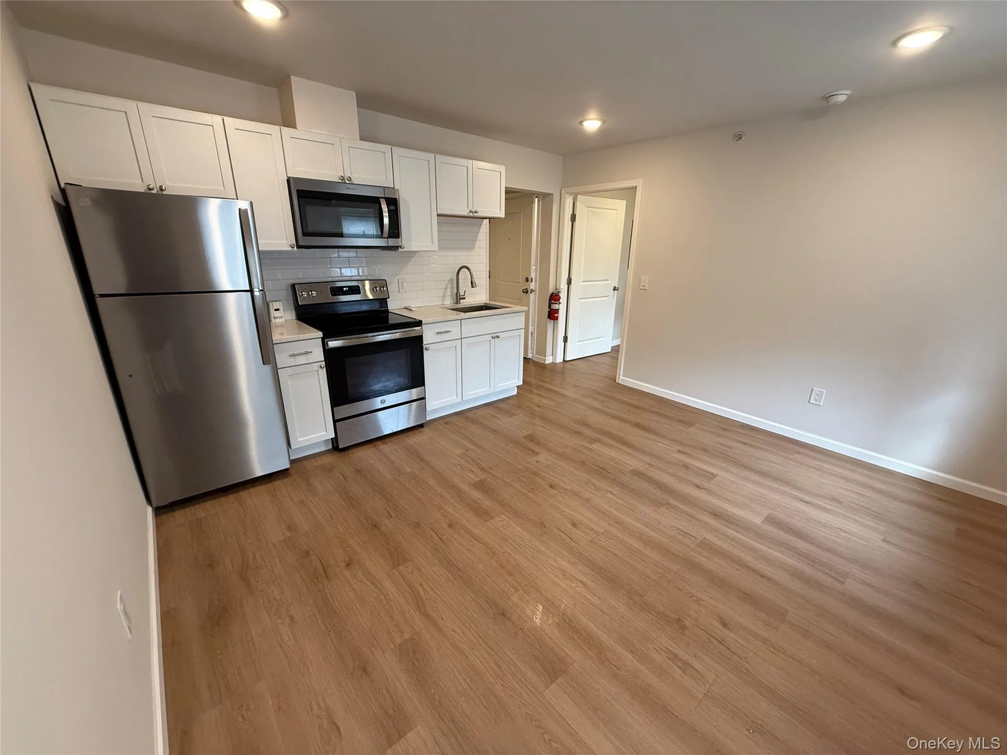 Kitchen with stainless steel appliances, light countertops, white cabinets, and light wood-type flooring Kitchen with stainless steel appliances, light countertops, white cabinets, and light wood-type flooring