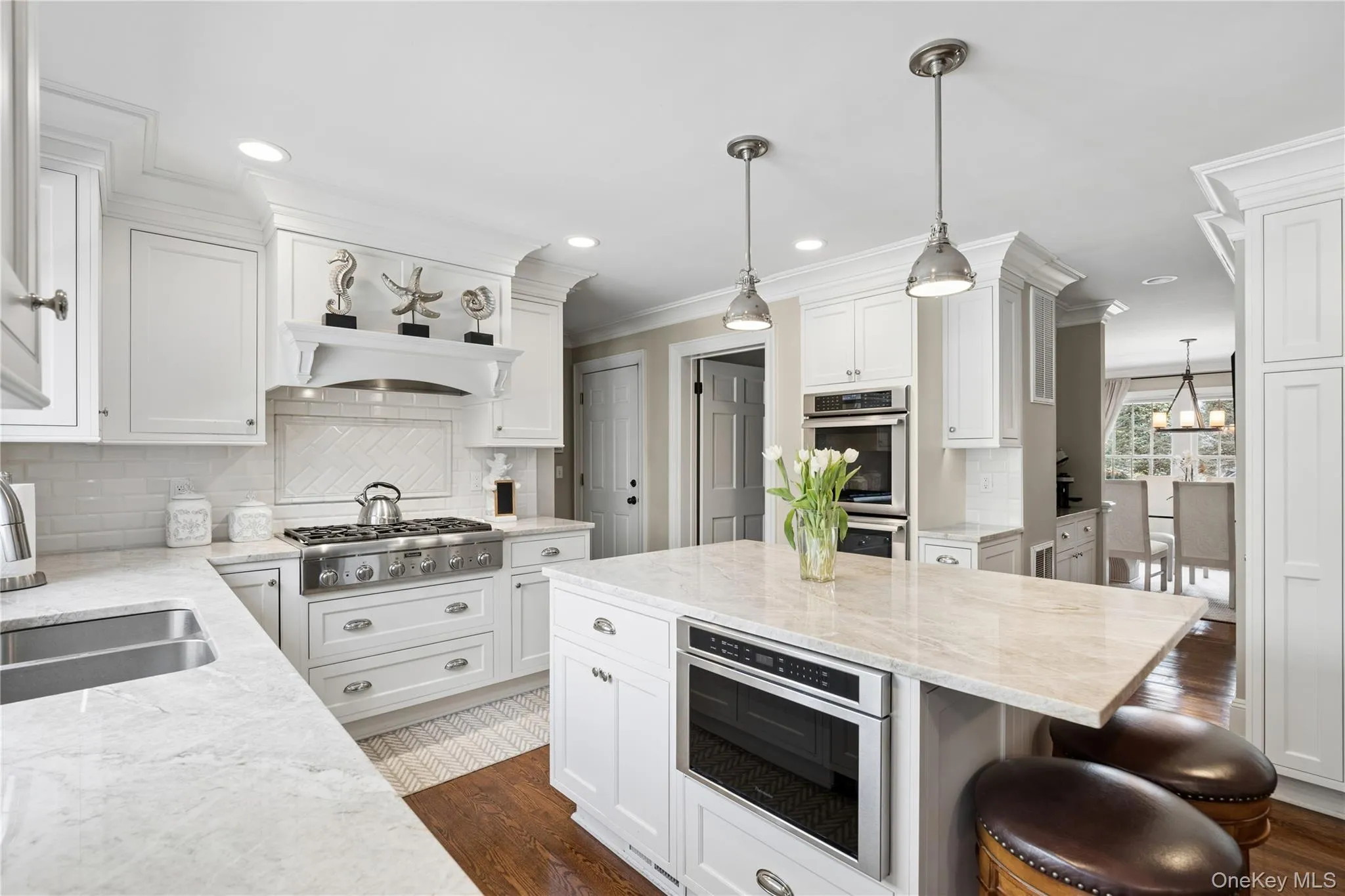 Open-concept eat -kitchen featuring hardwood flooring, white cabinetry, a center island with quartzite countertop and top tier stainless steel appliances, Open-concept eat -kitchen featuring hardwood flooring, white cabinetry, a center island with quartzite countertop and top tier stainless steel appliances,