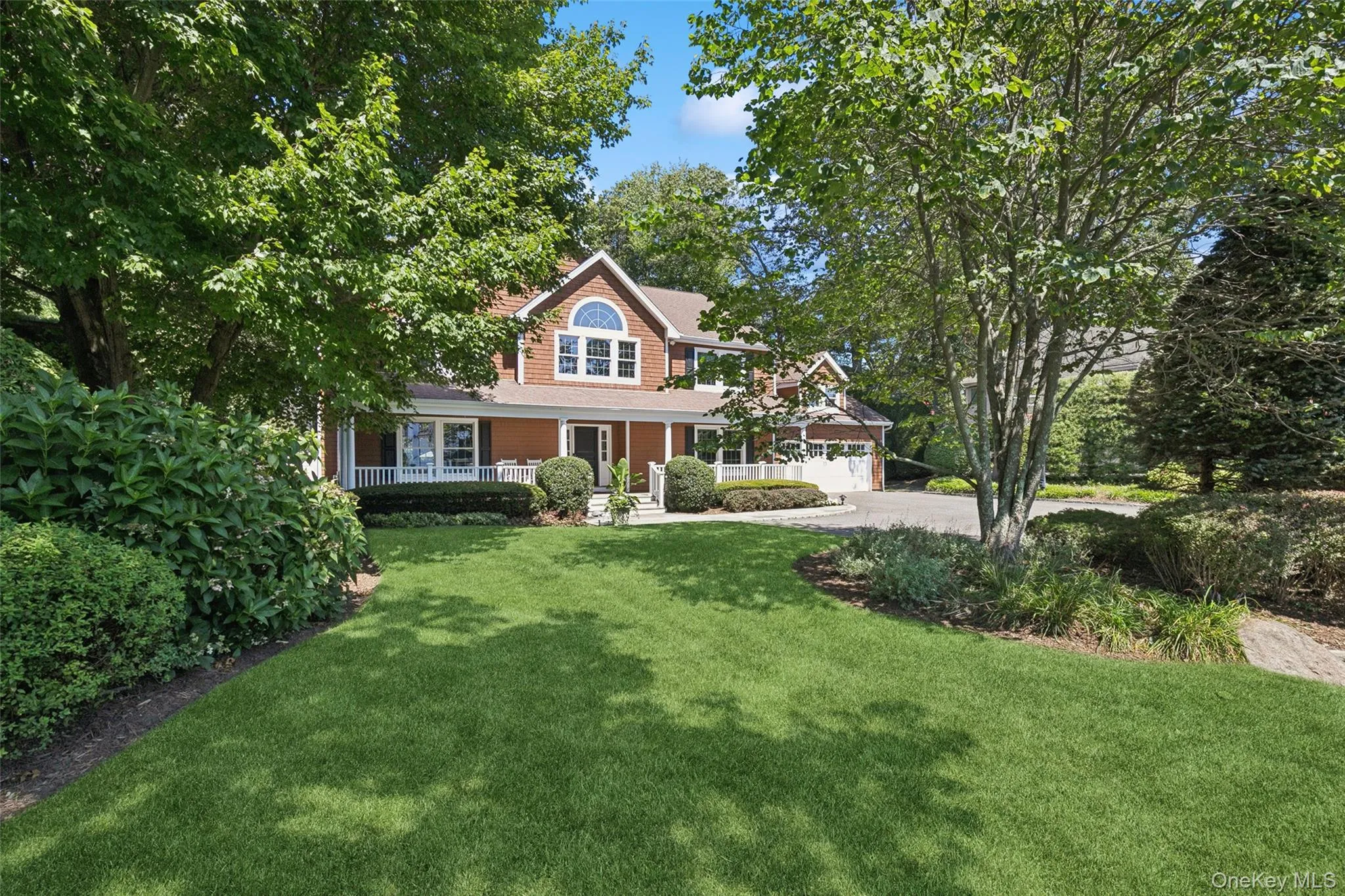 Two-story property featuring a front porch with white railing, a dormer window, and an attached two-car garage Two-story property featuring a front porch with white railing, a dormer window, and an attached two-car garage