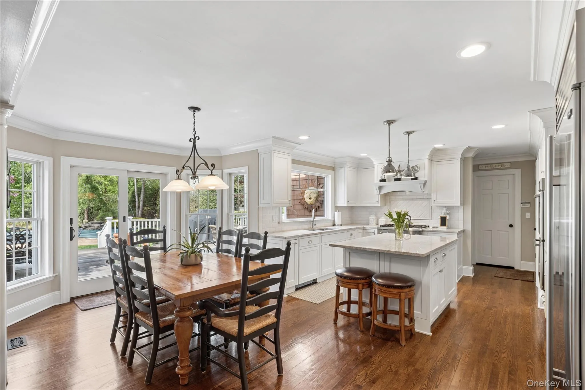 Open-concept eat -kitchen featuring hardwood flooring, white cabinetry, a center island with quartzite countertop and top tier stainless steel appliances Open-concept eat -kitchen featuring hardwood flooring, white cabinetry, a center island with quartzite countertop and top tier stainless steel appliances
