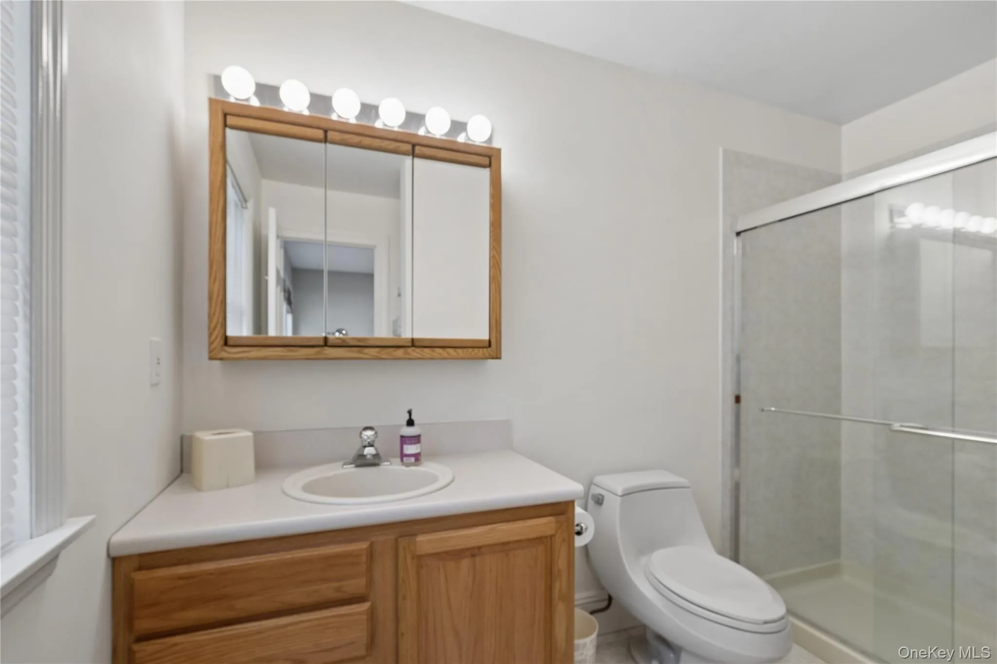Bathroom featuring a single vanity with wood-finish cabinetry, a white countertop, Bathroom featuring a single vanity with wood-finish cabinetry, a white countertop,