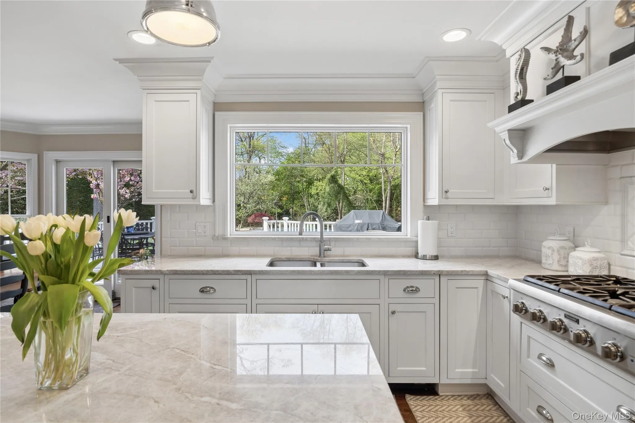 Open-concept eat -kitchen featuring hardwood flooring, white cabinetry, a center island with quartzite countertop and top tier stainless steel appliances Open-concept eat -kitchen featuring hardwood flooring, white cabinetry, a center island with quartzite countertop and top tier stainless steel appliances