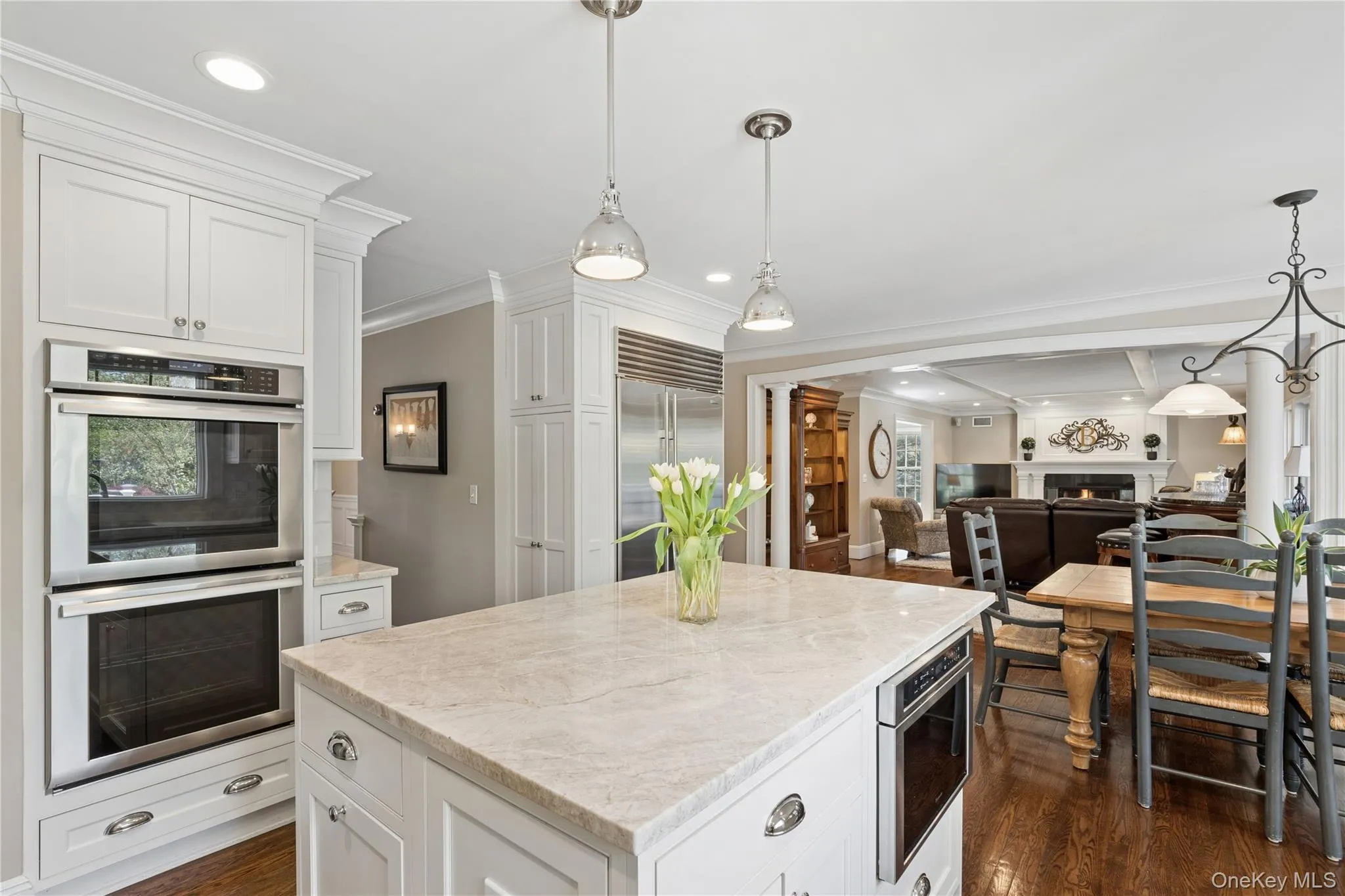 Open-concept eat -kitchen featuring hardwood flooring, white cabinetry, a center island with quartzite countertop and top tier stainless steel appliances, Open-concept eat -kitchen featuring hardwood flooring, white cabinetry, a center island with quartzite countertop and top tier stainless steel appliances,