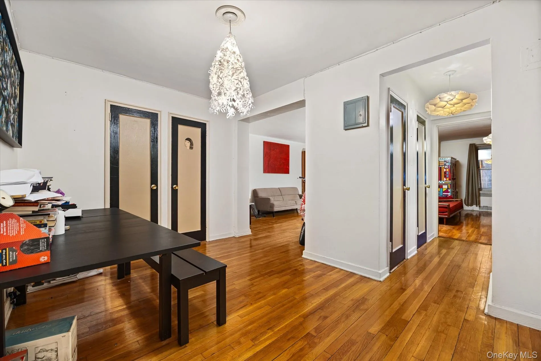 Wood-finish flooring extends throughout this interior space, featuring white walls and multiple doorways Wood-finish flooring extends throughout this interior space, featuring white walls and multiple doorways