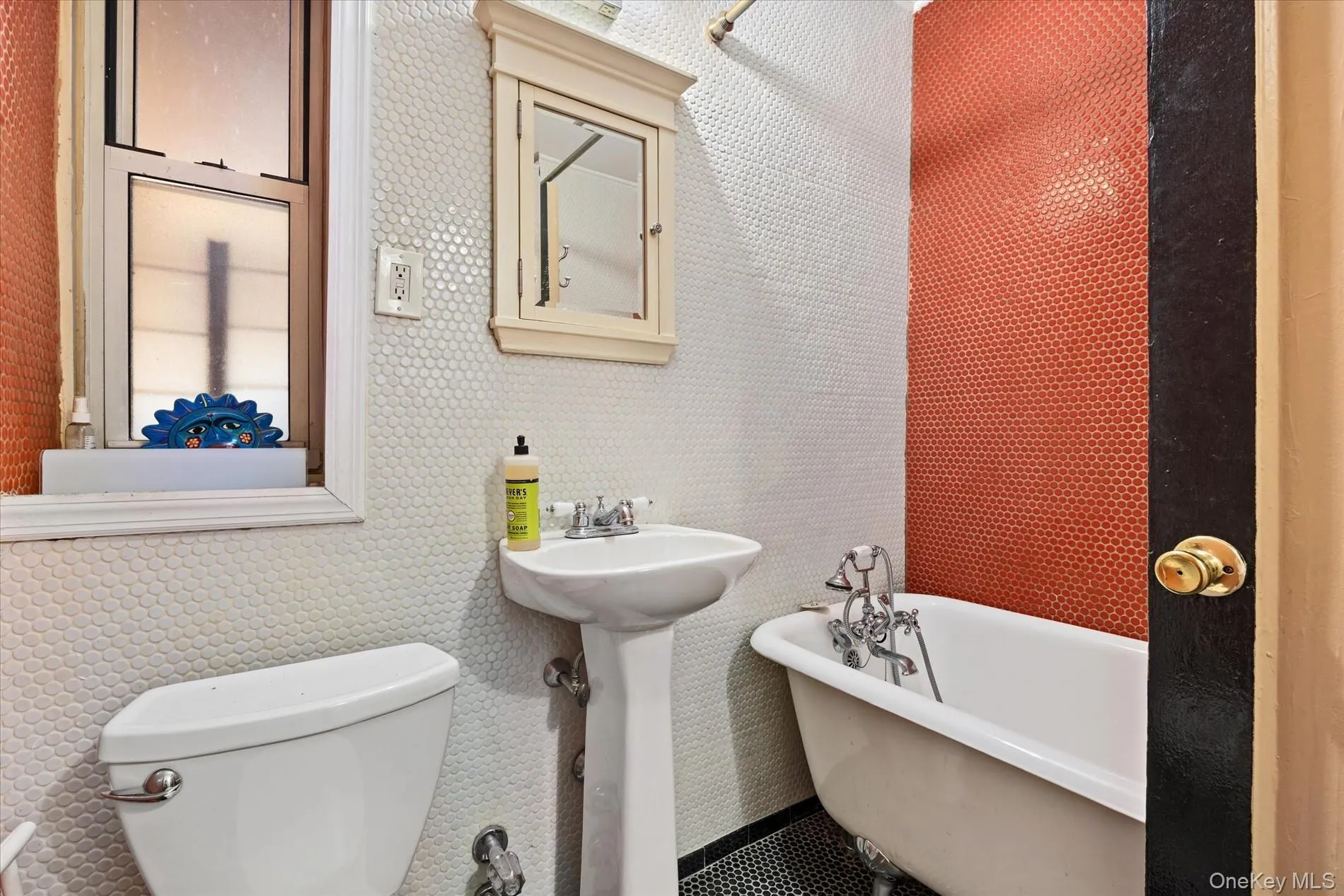 Bathroom featuring white penny tile walls, a white pedestal sink, and a clawfoot tub Bathroom featuring white penny tile walls, a white pedestal sink, and a clawfoot tub
