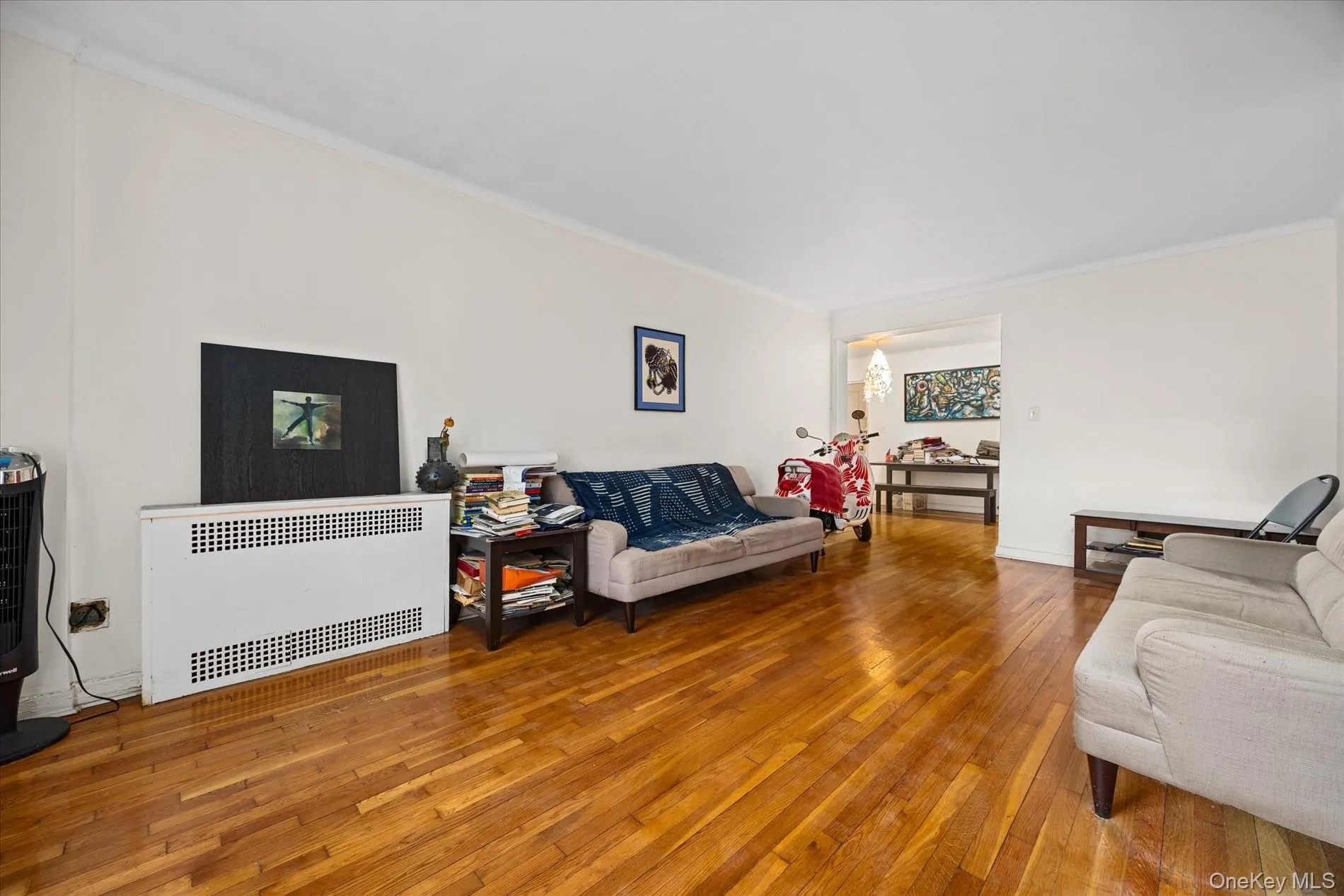 Hardwood flooring throughout a living area featuring white walls and crown molding Hardwood flooring throughout a living area featuring white walls and crown molding
