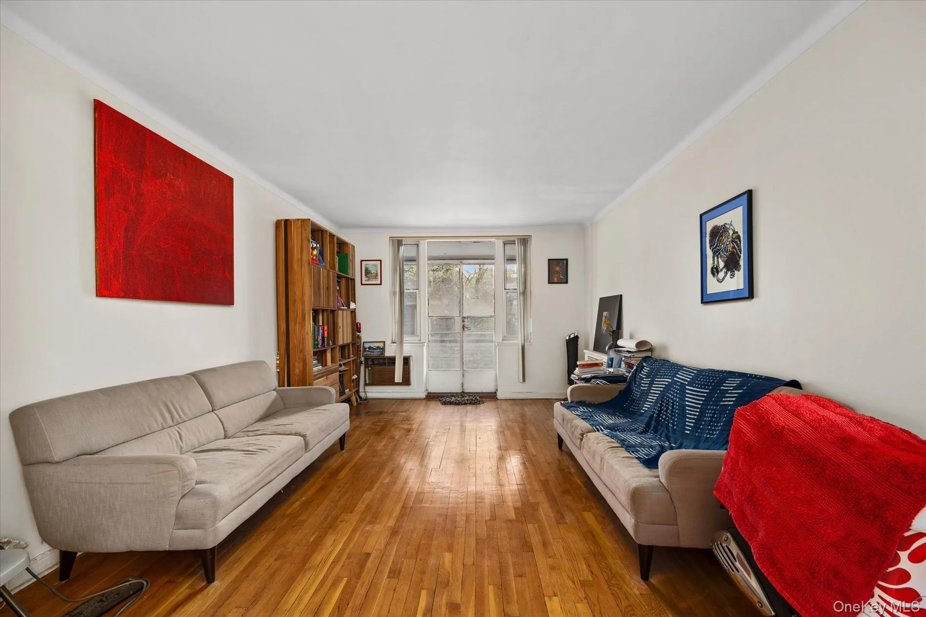 Expansive living area featuring wood-finish flooring, white walls, and crown molding Expansive living area featuring wood-finish flooring, white walls, and crown molding