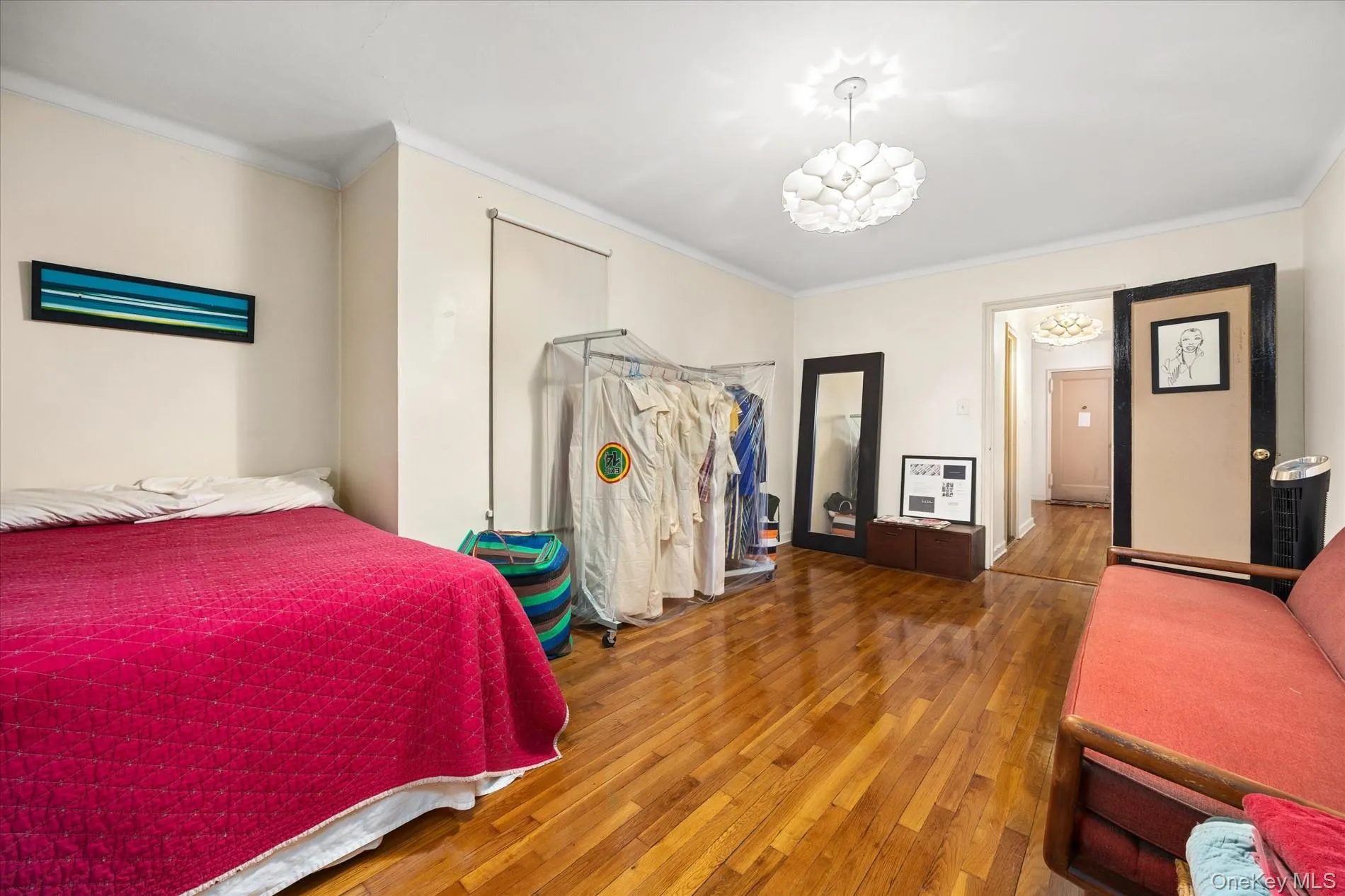 Hardwood-finish flooring throughout, featuring crown molding, a decorative ceiling light fixture, and a neutral wall palette Hardwood-finish flooring throughout, featuring crown molding, a decorative ceiling light fixture, and a neutral wall palette