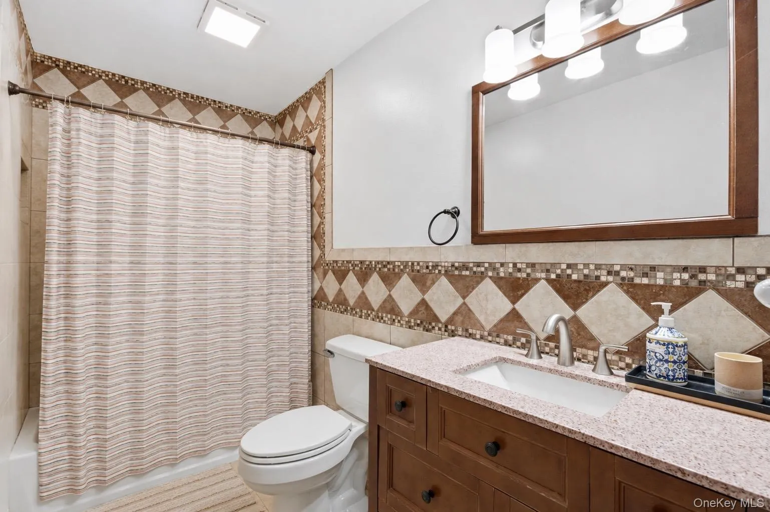 Full bathroom featuring a vanity with a light-colored countertop, an undermount sink, and a framed mirror Full bathroom featuring a vanity with a light-colored countertop, an undermount sink, and a framed mirror