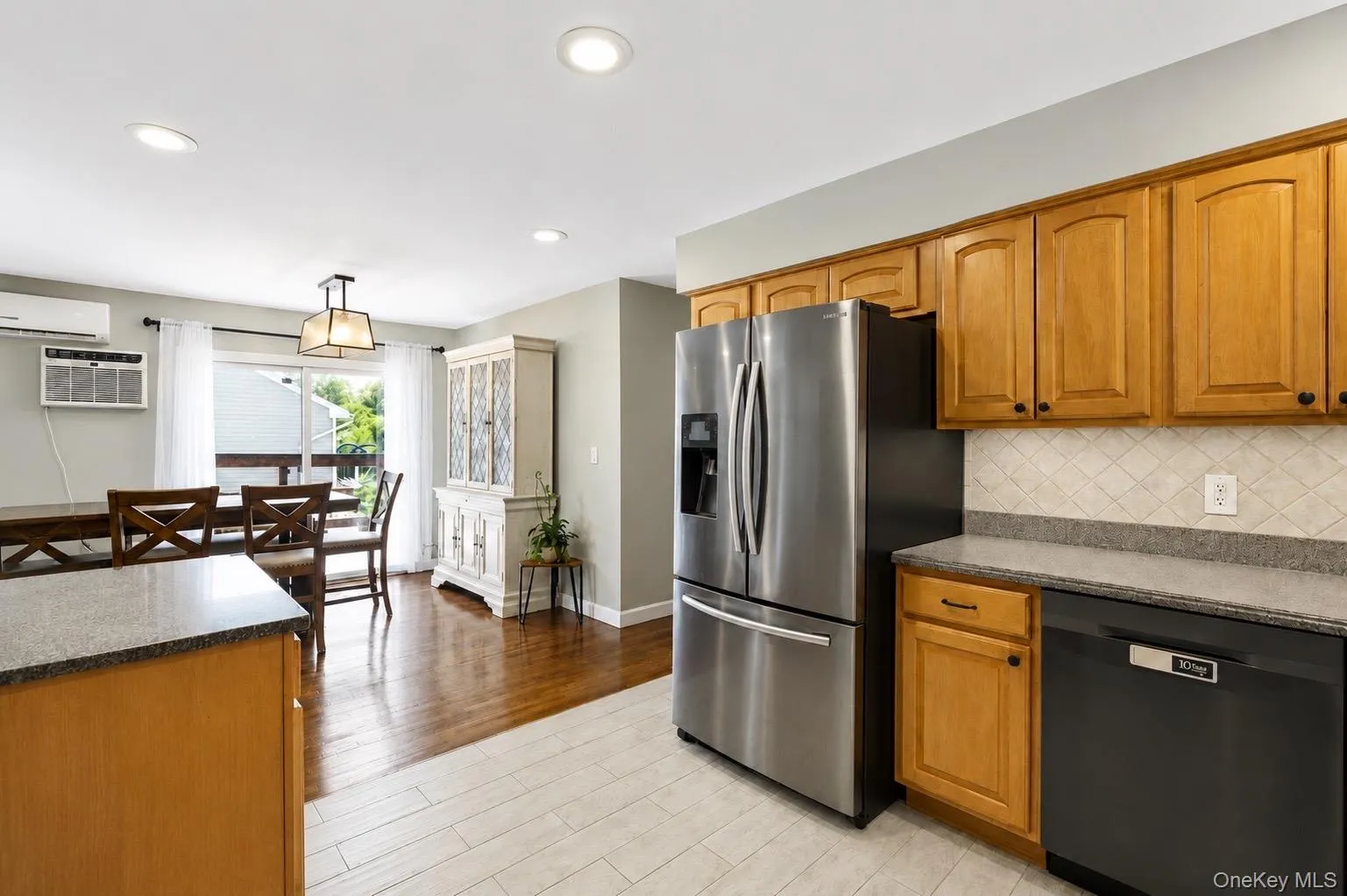 Kitchen and dining area featuring a stainless steel refrigerator, dishwasher and light wood cabinetry Kitchen and dining area featuring a stainless steel refrigerator, dishwasher and light wood cabinetry