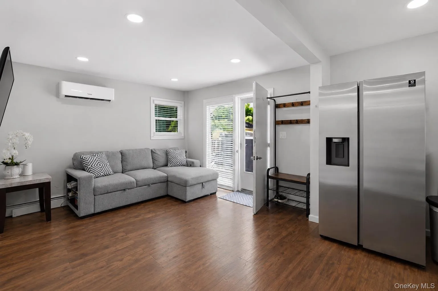 Open-concept living space with wood-finish flooring, recessed lighting, and a ductless mini-split system Open-concept living space with wood-finish flooring, recessed lighting, and a ductless mini-split system