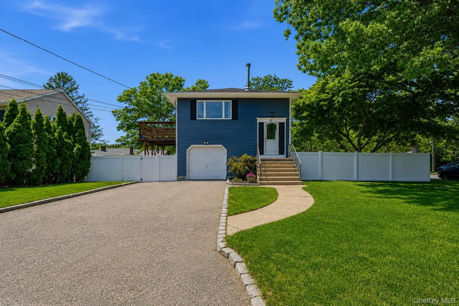 Hi Ranch set back from the road on a corner lot, featuring blue siding, a white garage door, and a white front entry door with side lights Hi Ranch set back from the road on a corner lot, featuring blue siding, a white garage door, and a white front entry door with side lights